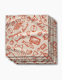 The Geometry Summer Air Dinner Napkin Set features eco-friendly napkins with red Italian food illustrations—fish, fruit, wine, cheese, and sardine cans—and words like mangia bene and dolce on a cream background.