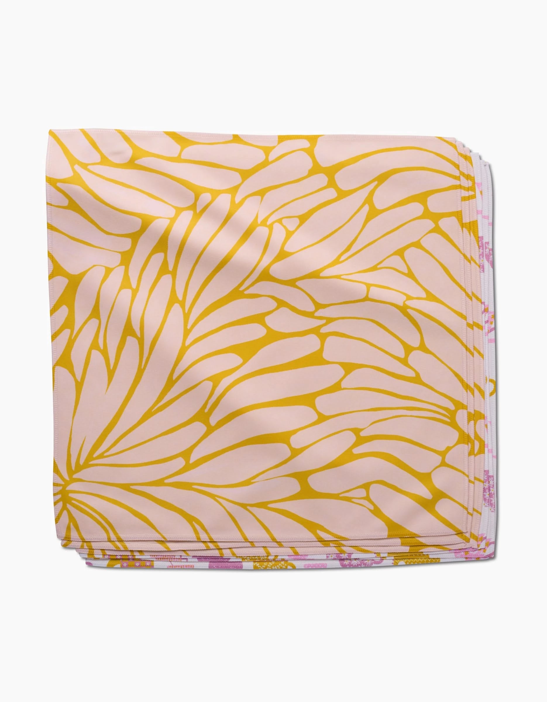 The GEOMETRY Tenderhearted Dinner Napkin is made from Geosuede fabric, showcasing a light pink base with a bold, abstract yellow petal-like pattern.
