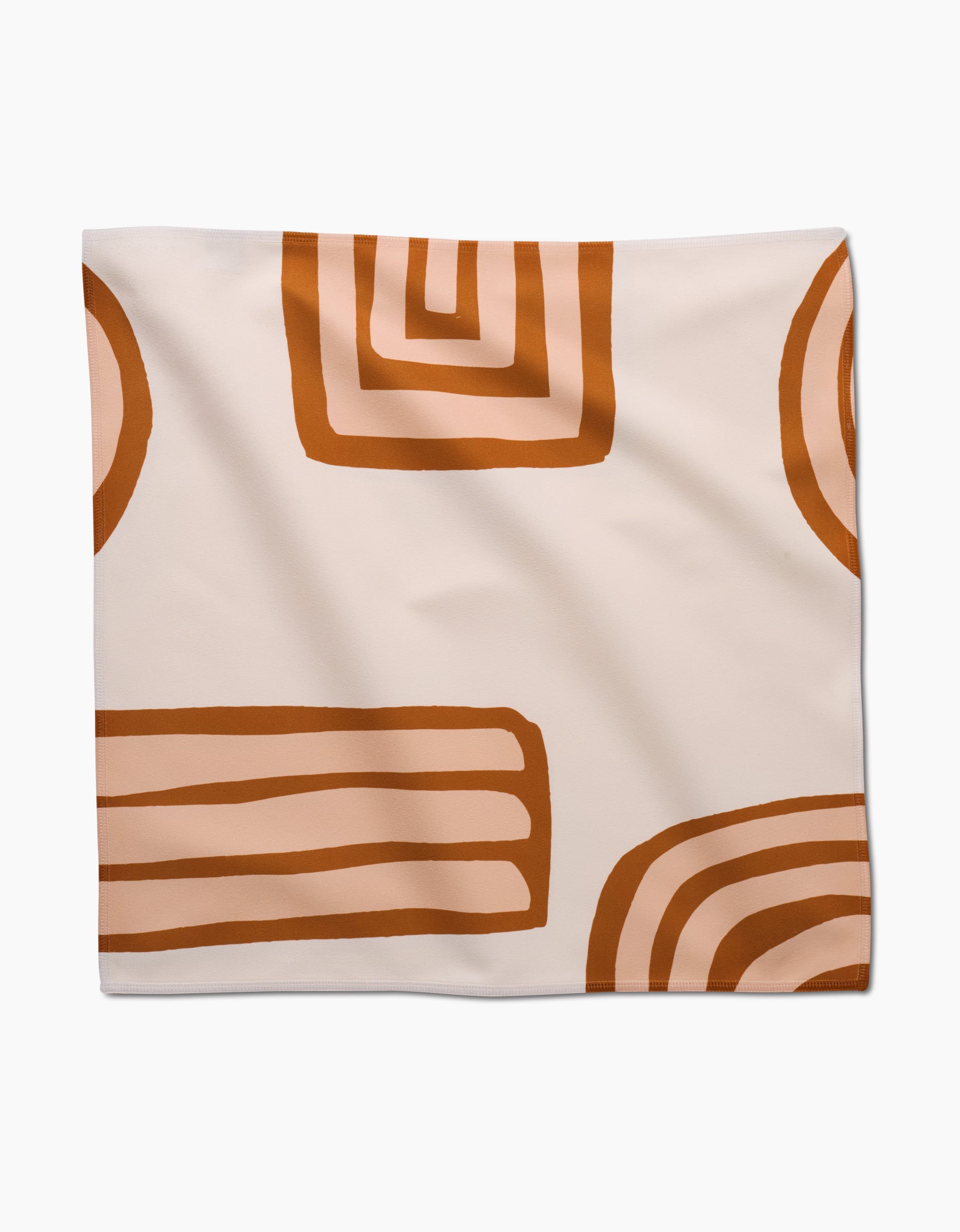 The GEOMETRY Terracotta Vibes napkin features a cream background with abstract brown and orange geometric shapes, such as rectangles, half-circles, and concentric lines.