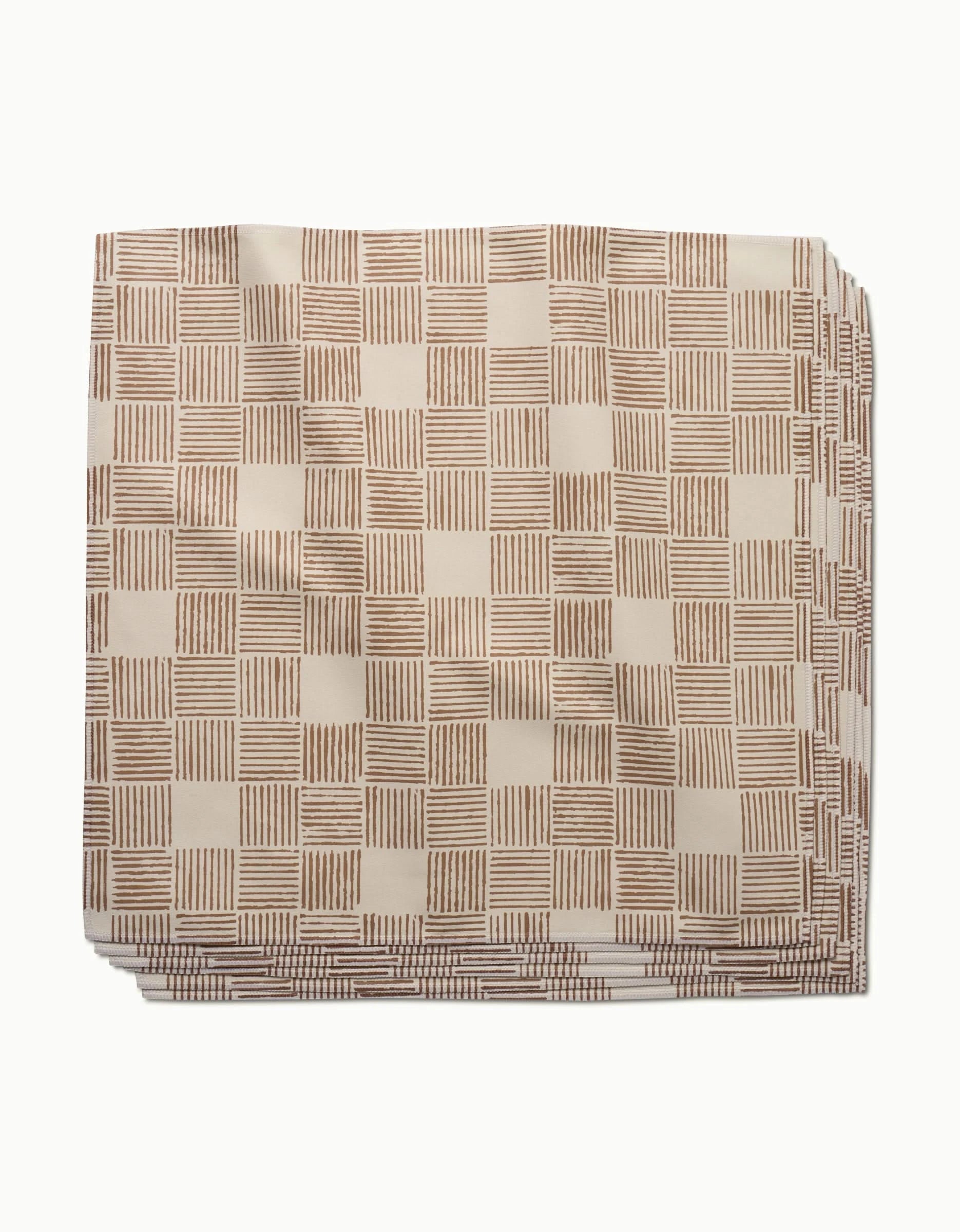 The Thatcher napkin by Studio Jeannot is a neatly folded beige cloth napkin made from premium Geosuede, featuring a checkered pattern with horizontal and vertical brown stripes.