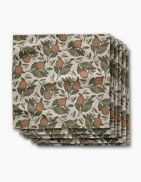 Geometry’s Valencia placemats feature a botanical orange and green leaf print on a cream background, arranged in an overlapping stack—perfect for pairing with absorbent cloth napkins for a coordinated dining table.