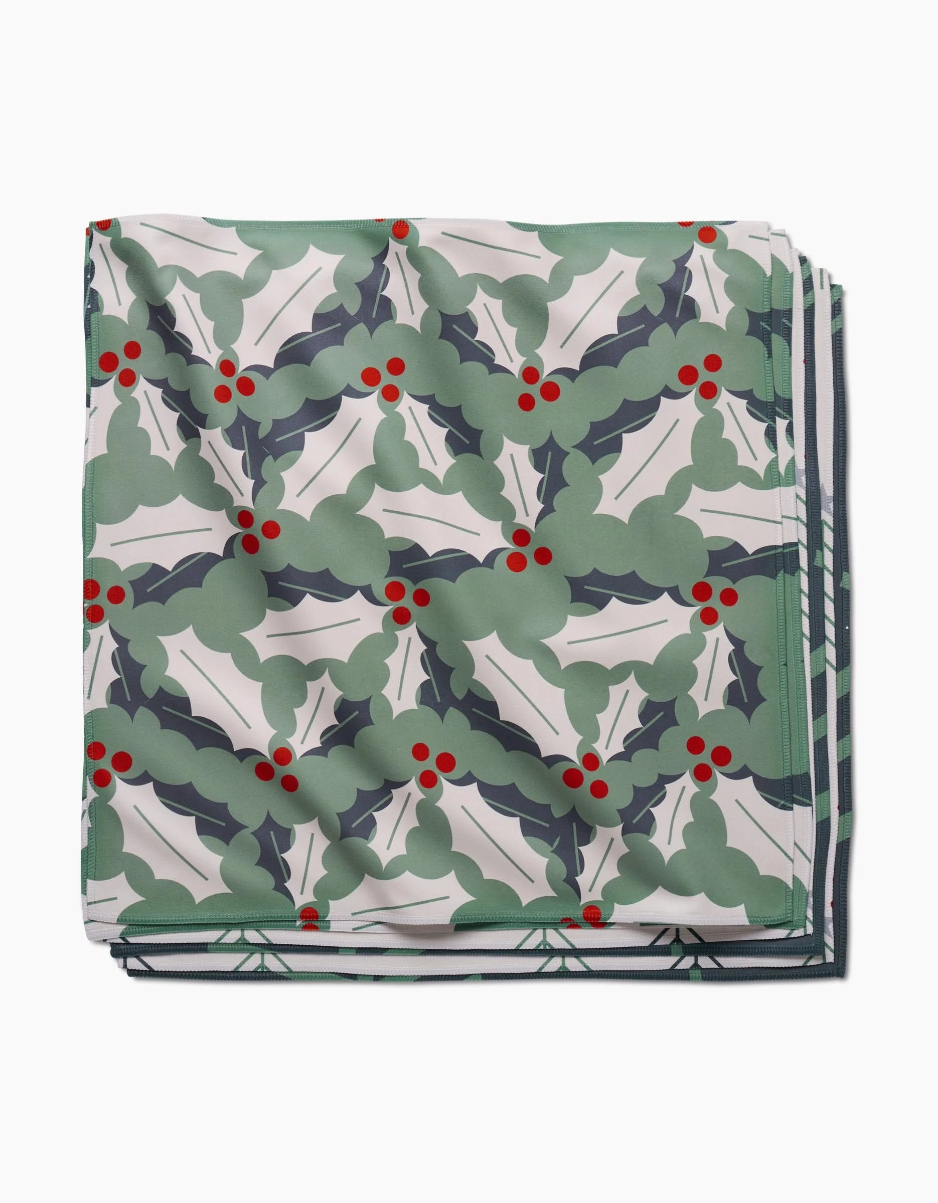 The Winter Wonderful scarf by Lizzie Clark features green holly leaves and red berries on white, ideal as an eco-friendly, reusable napkin for festive gatherings.