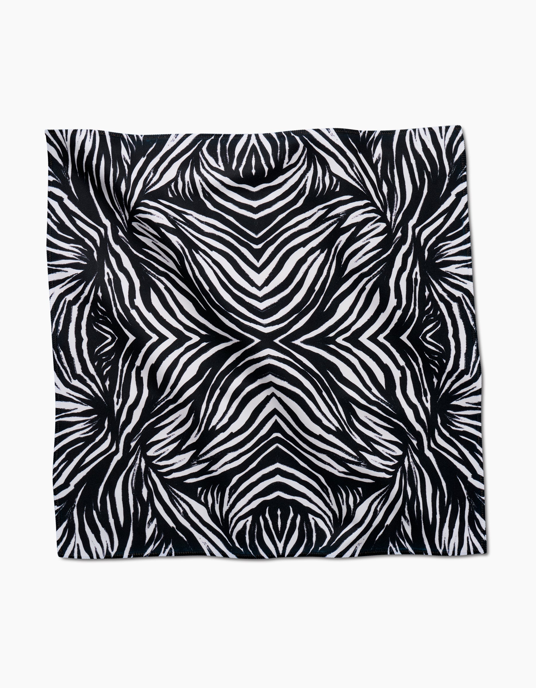The GEOMETRY Zebra dinner napkin is crafted from soft, recycled Geosuede fabric and features a bold, symmetrical black and white zebra stripe pattern on a white background.