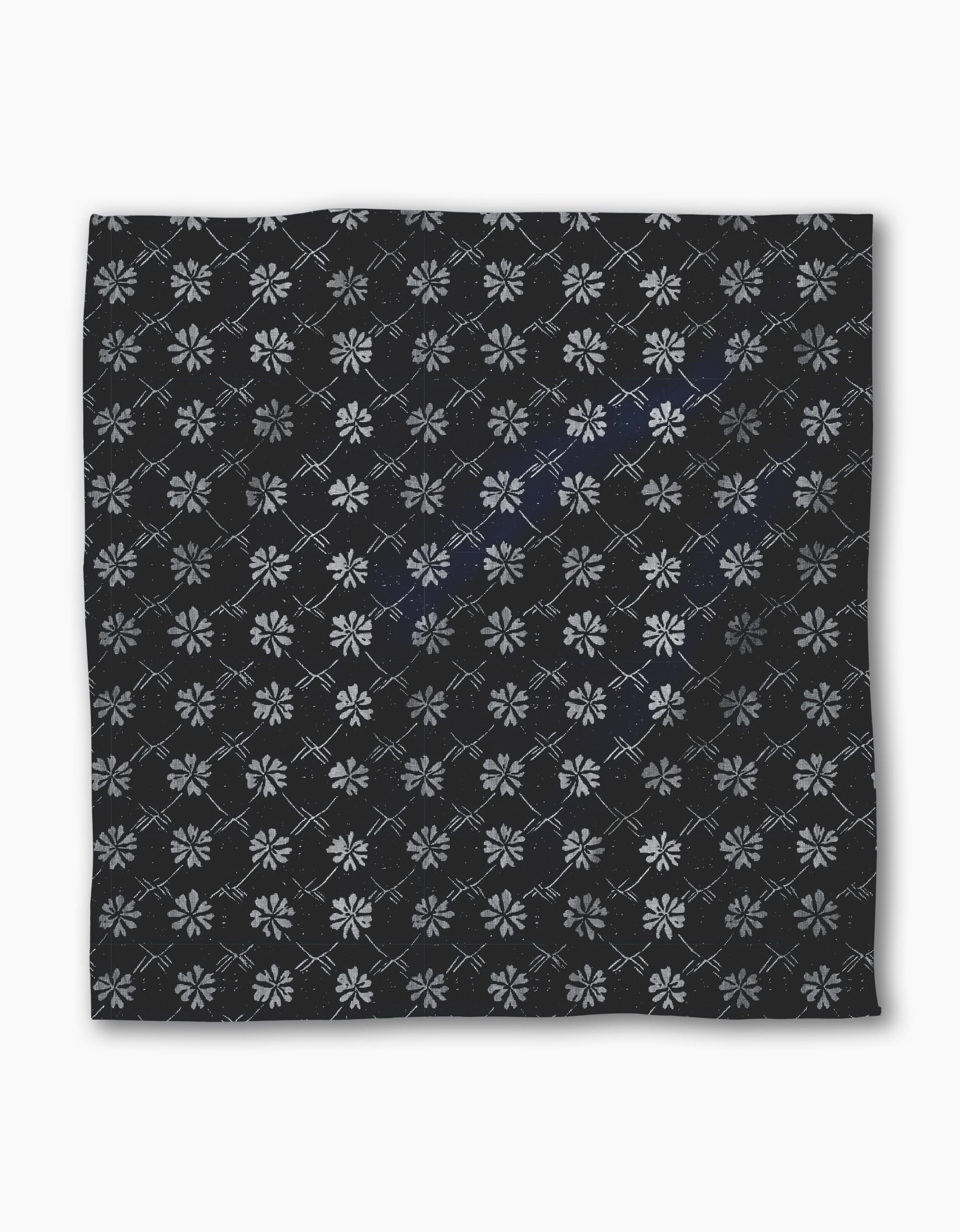 The Geometry Bonnie Indigo is a square black recycled dinner napkin featuring light gray geometric floral patterns and intersecting diamond lines, combining style and absorbency for any dinner setting.