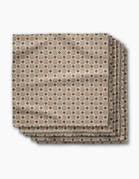 Four absorbent dinner napkins from Geometry’s Heritage Stamp collection feature a geometric brown and beige diamond pattern, neatly folded and displayed on a white background—perfect for adding style to your table.