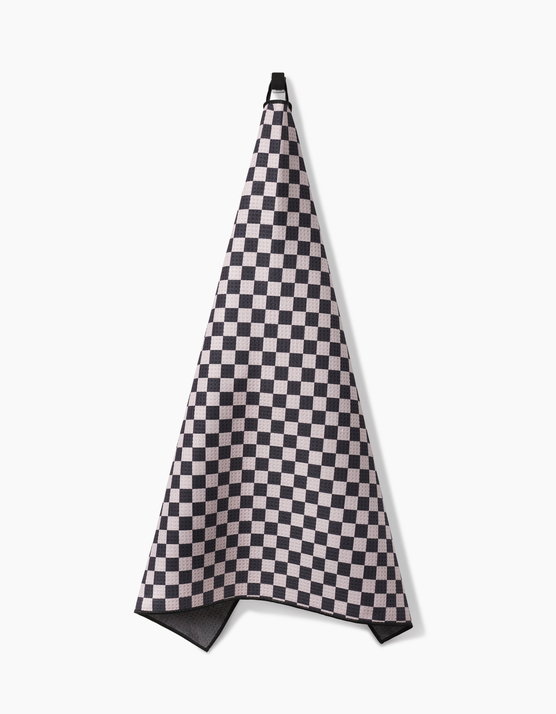 The Geometry Cool Pup towel, featuring a black and white checkered design, hangs absorbently on a hook against a plain white background.