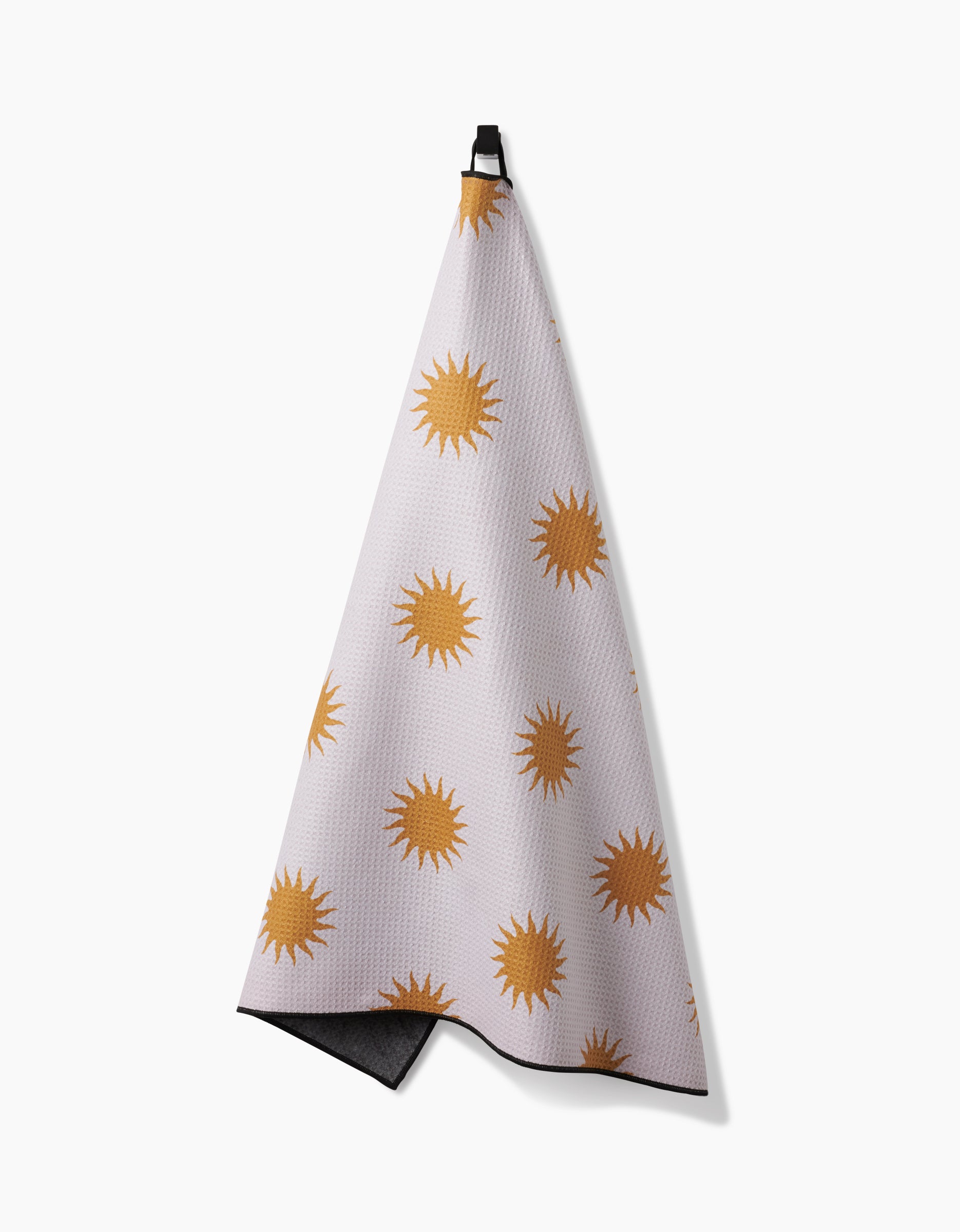 The Geometry Feeling Sunny towel, featuring golden yellow sun shapes on white, hangs from a black loop for easy drying—making it a quick-dry, practical choice for your bath or as a dog towel.