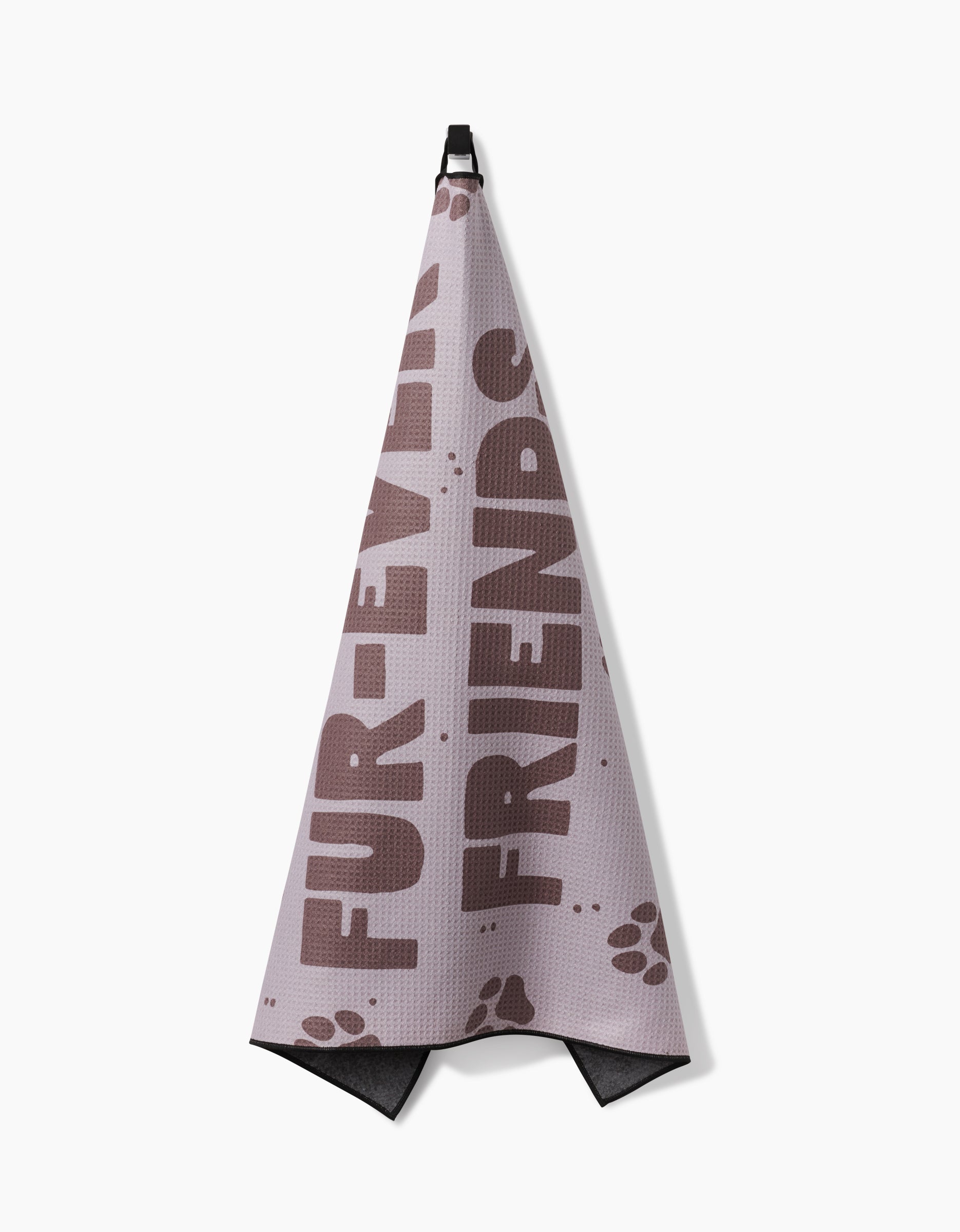 The Geometry Fur Ever Friends pink dog towel, made from recycled materials, features brown FUR-EVER FRIENDS text and paw prints along the bottom. Its highly absorbent and hangs from a black hook.