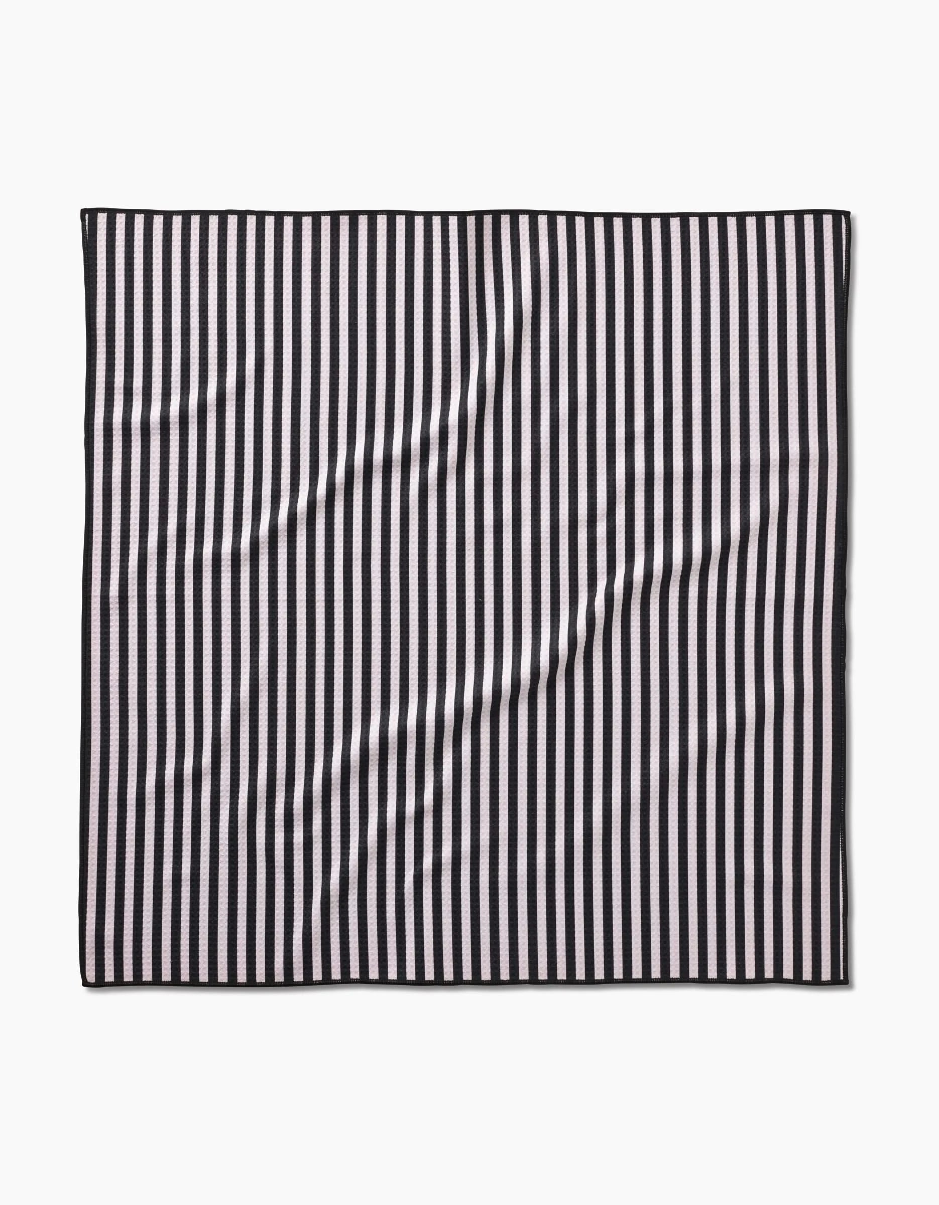 The Geometry Good Pup rectangular dog towel features evenly spaced vertical black and white stripes, slight wrinkles, and is made from recycled materials. Displayed on a plain white background.