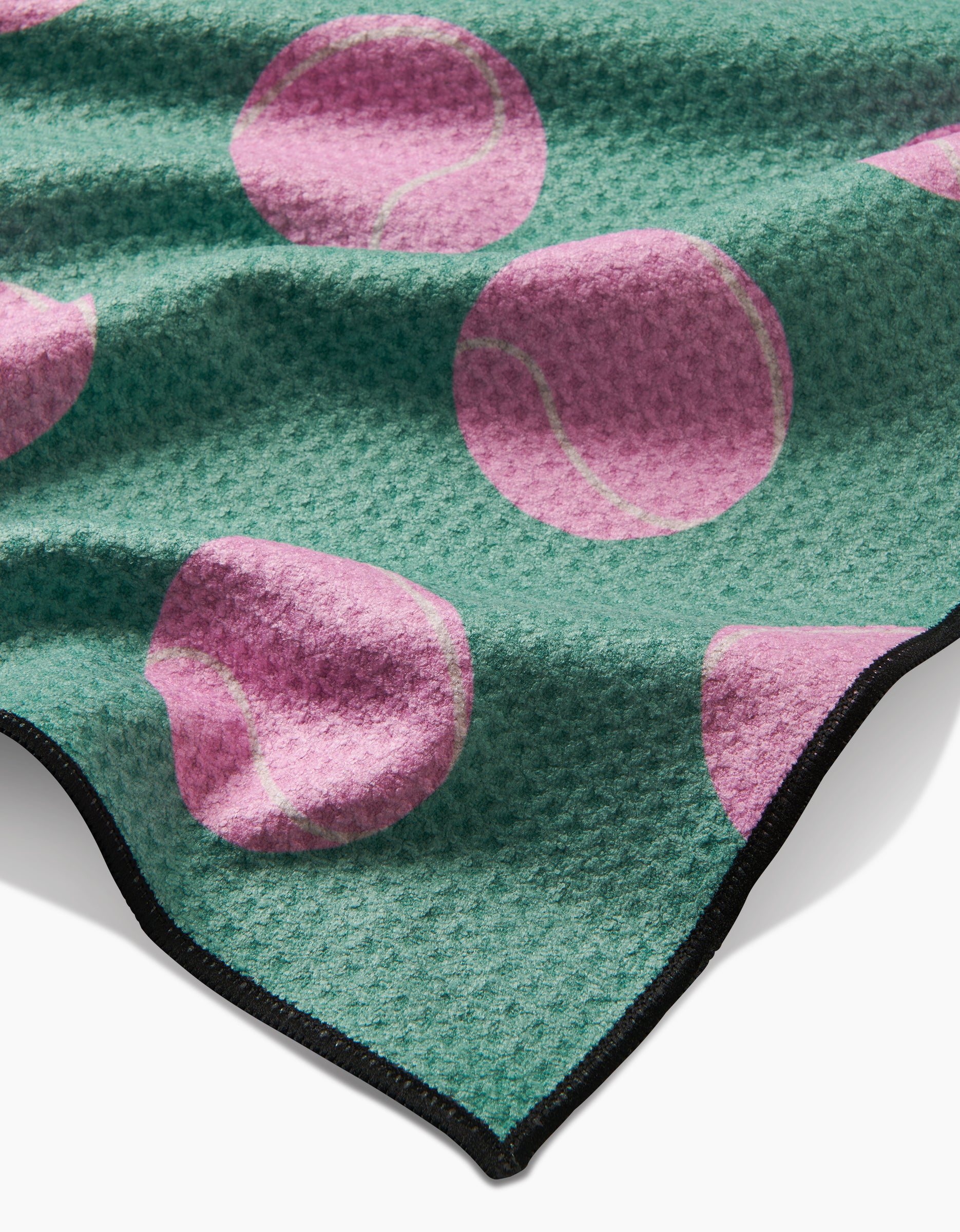 The Geometry Pink Ball is a green textured dog towel made from recycled materials, featuring large pink tennis ball patterns and a black edge trim.