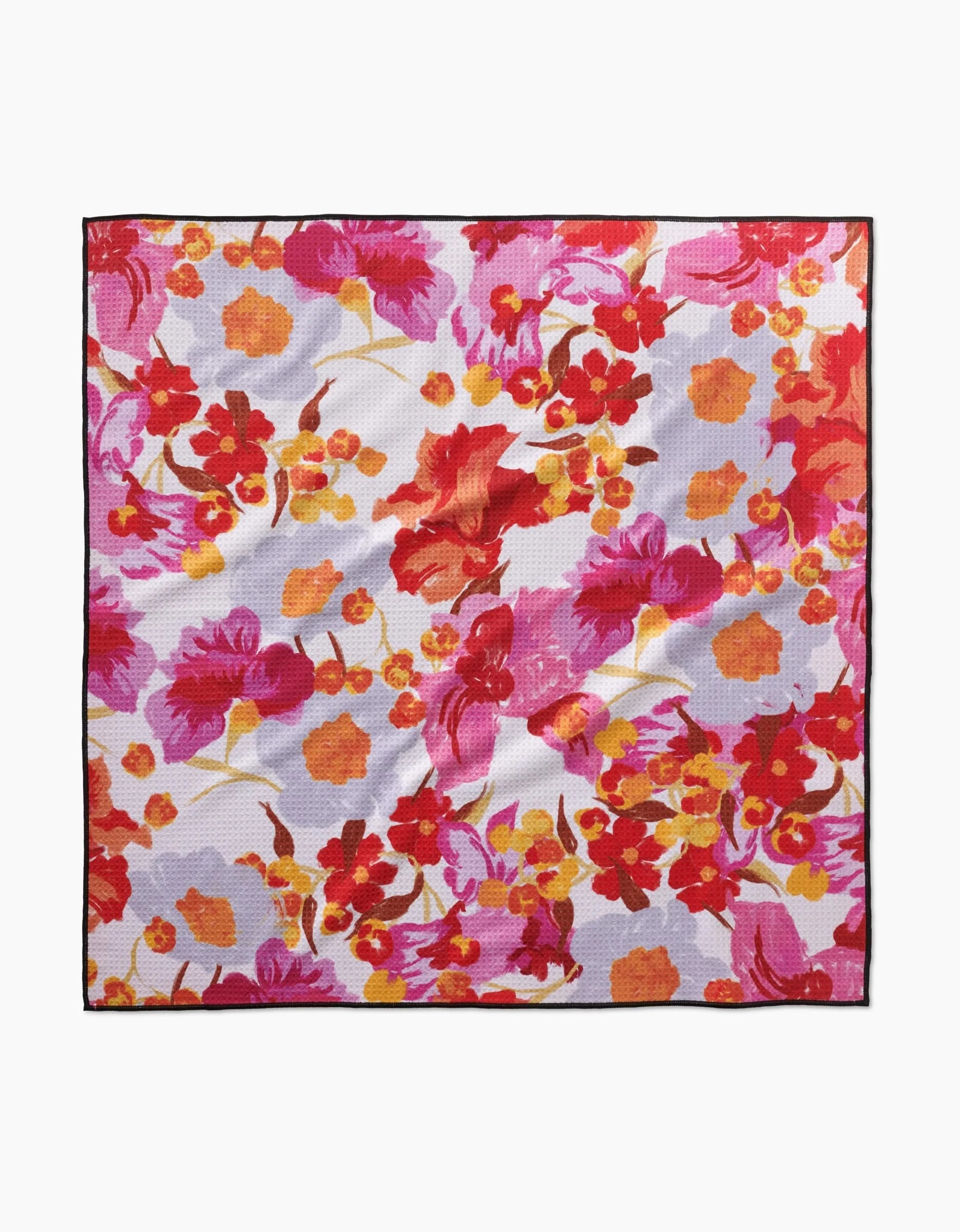 The Geometry Pup Florals scarf features a vibrant floral print in red, orange, pink, and yellow on a light background, crafted from recycled materials with a thin black border for a stylish touch.