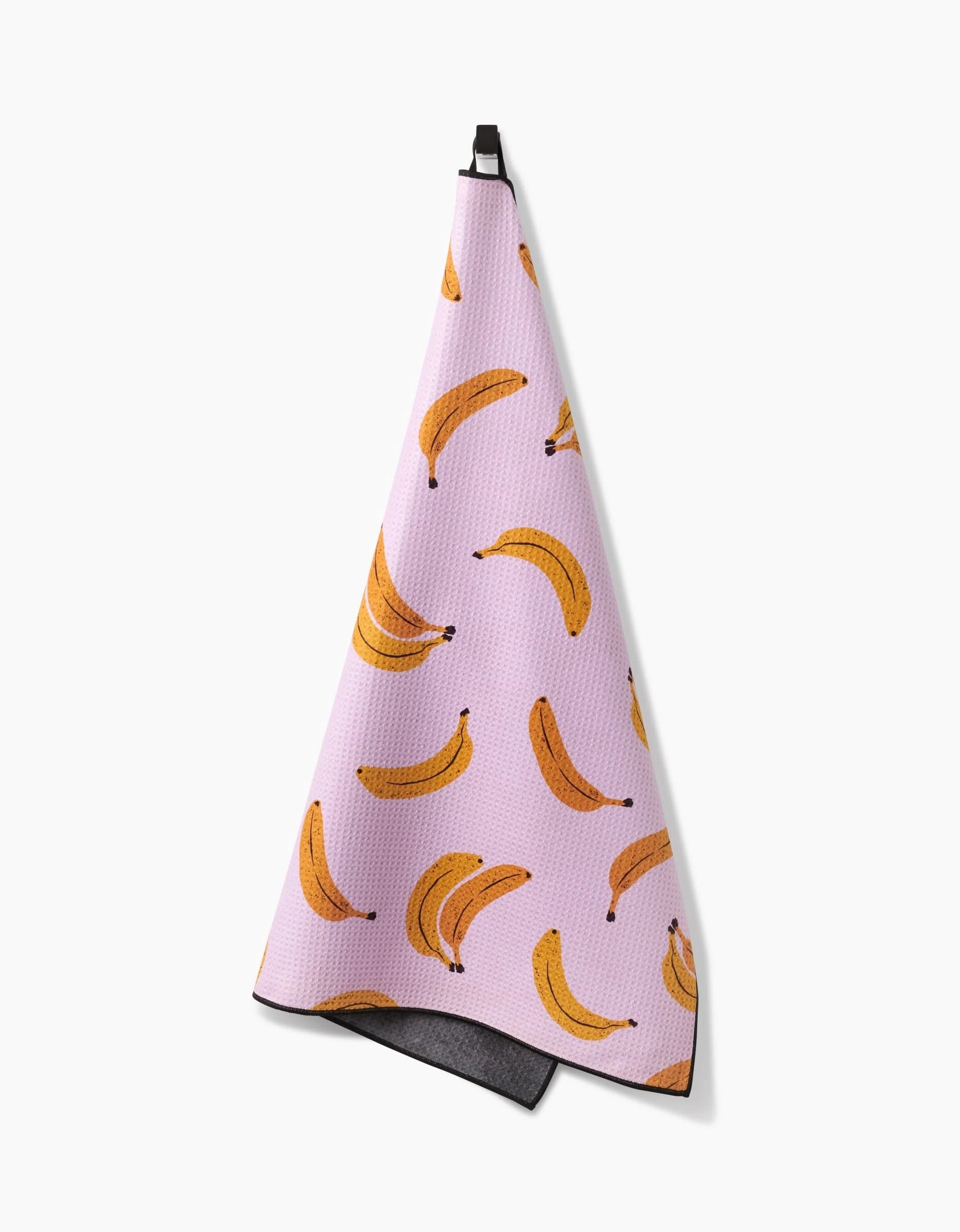 The Geometry Pupnana is a pink, highly absorbent dog towel featuring a repeating yellow banana pattern and a black hanging loop, shown against a white background.