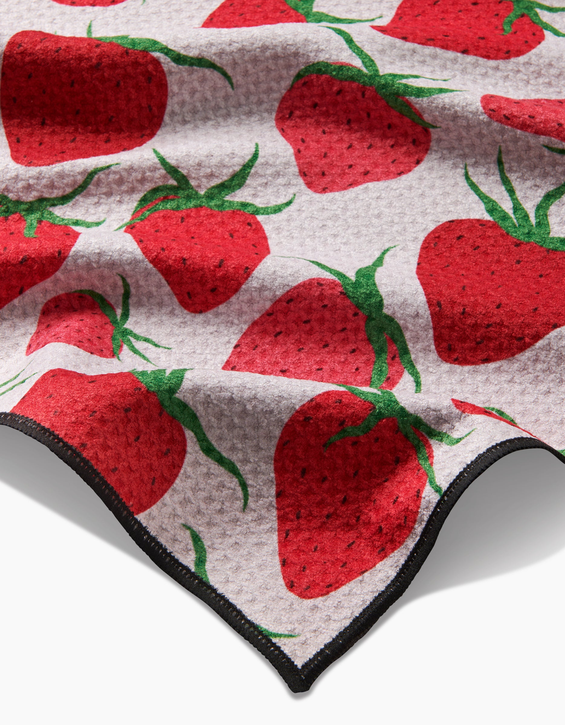 The Geometry Strawberry Sniff is a textured, absorbent towel featuring bold red strawberry patterns with green leaves on a light background and a black-edged border—an eco-friendly choice for your dog.