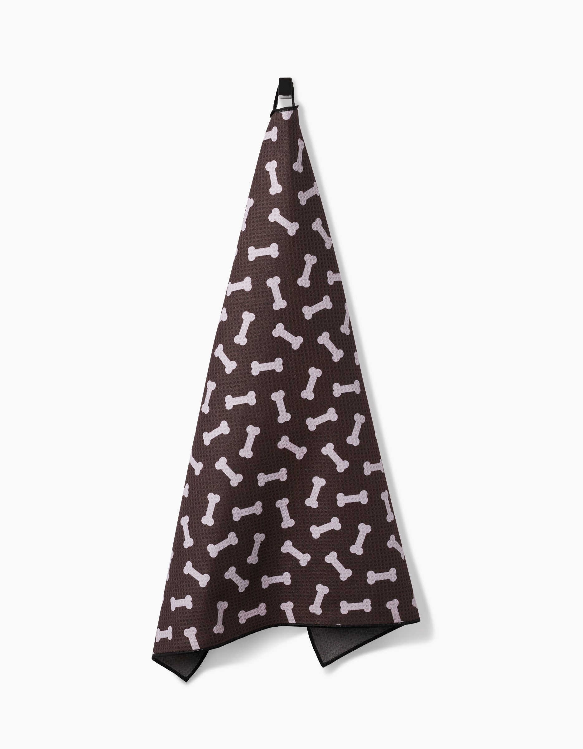 The Geometry Sweet Treats towel, made from highly absorbent recycled materials, features a playful dog bone pattern and hangs from a black loop against a white background.