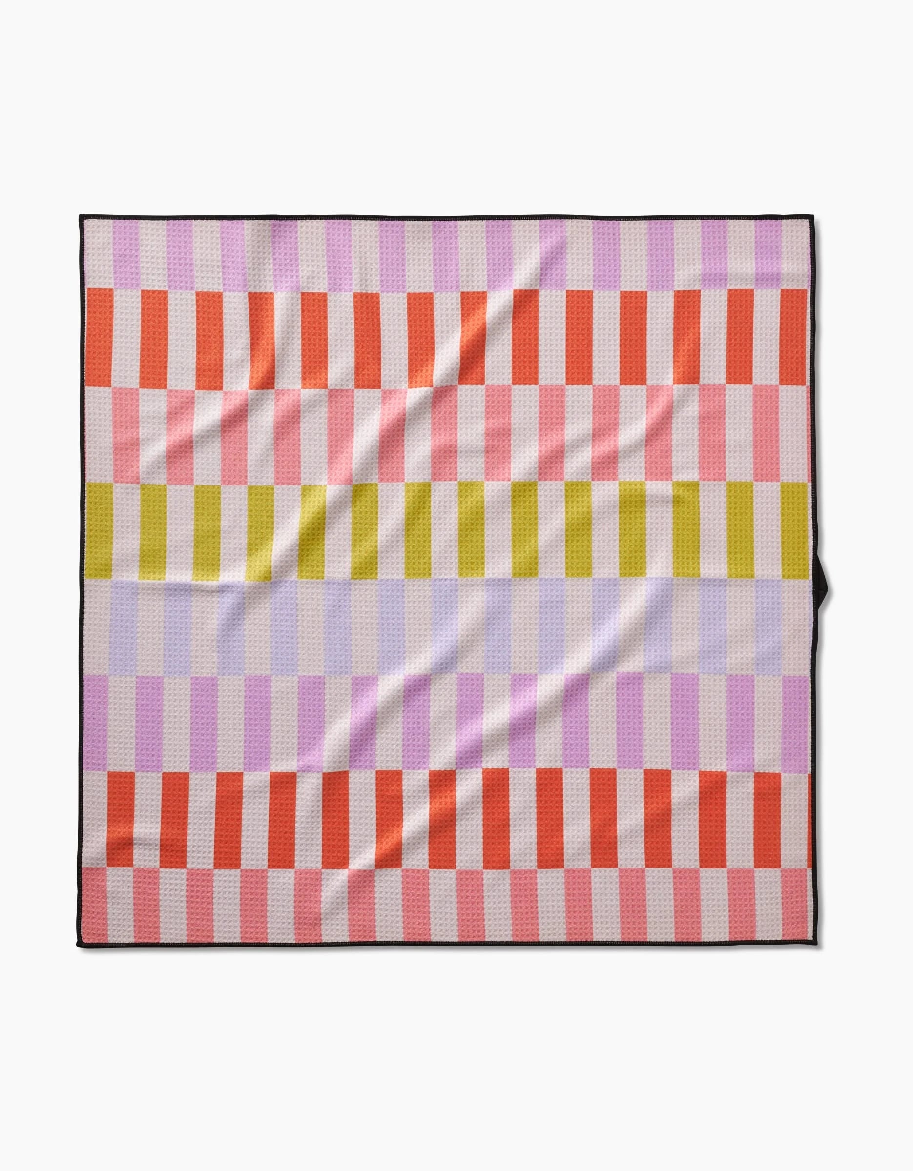 The Geometry Wag Wise blanket features a checkered pattern with horizontal stripes in red, light pink, yellow, and lavender, each formed by alternating squares. Made from recycled materials with a black border, it’s shown laid flat.