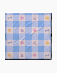 The Blue Sky Picnic Dreams dog towel by Letters By Shells features blue and white checks with pink flowers, purple paw prints, and light gray dog bones. Made from recycled materials, it’s finished with a dark blue border.