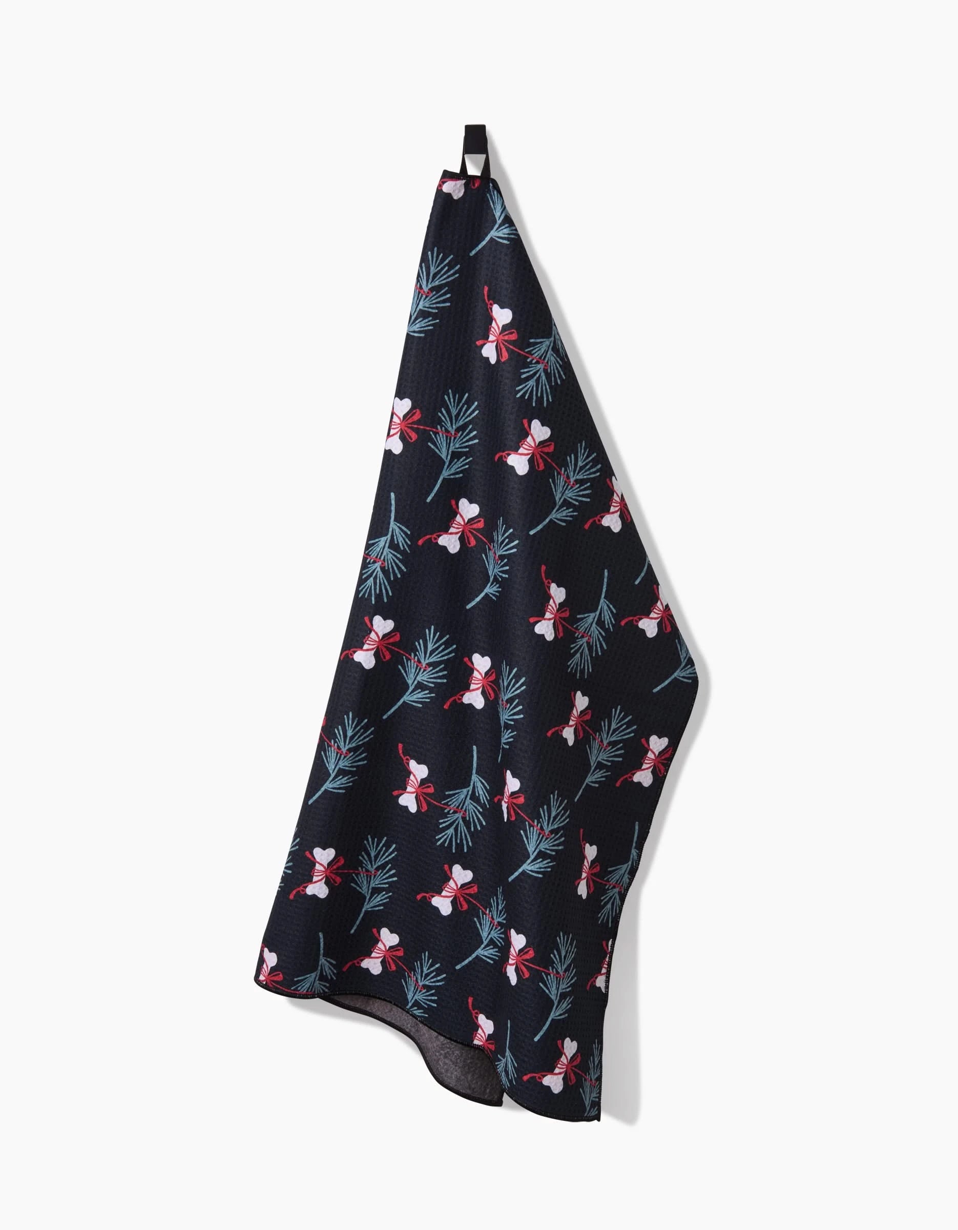 The Bones For Christmas kitchen towel by Charlie Rowan Designs, made from recycled materials, features a festive pattern with red and white Santa faces and green pine branches. It hangs by a black loop against a white background.