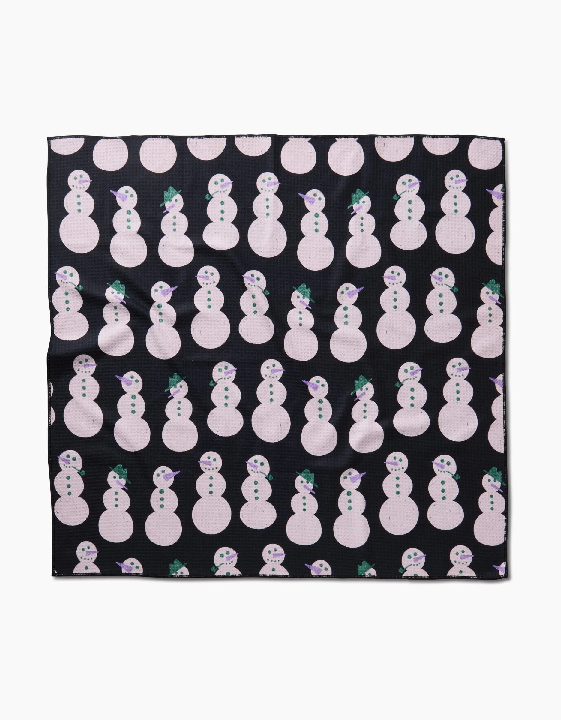 The Felicity Black recycled dog towel by Amy MacCready features rows of white snowmen with green hats and purple scarves on a black background.