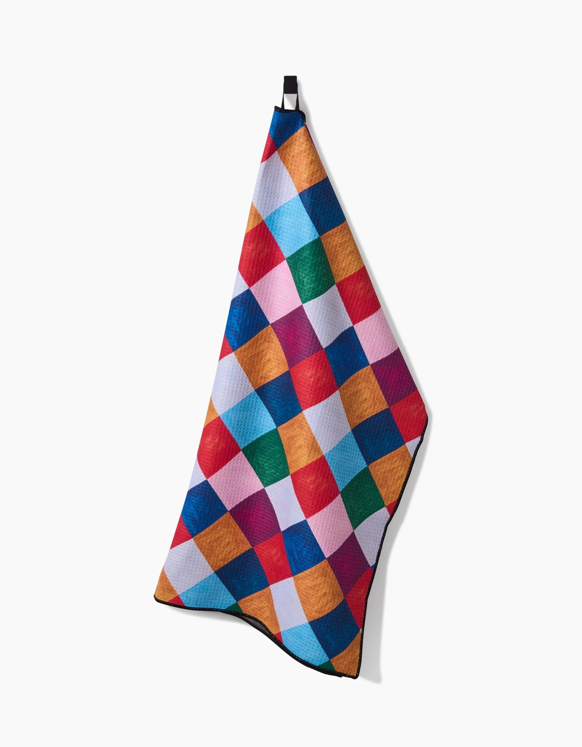 The Daria Solak Holiday Harlequin dog towel features a vibrant diamond patchwork in red, blue, orange, green, and pink. Highly absorbent, it hangs from a black loop and is displayed against a white background.