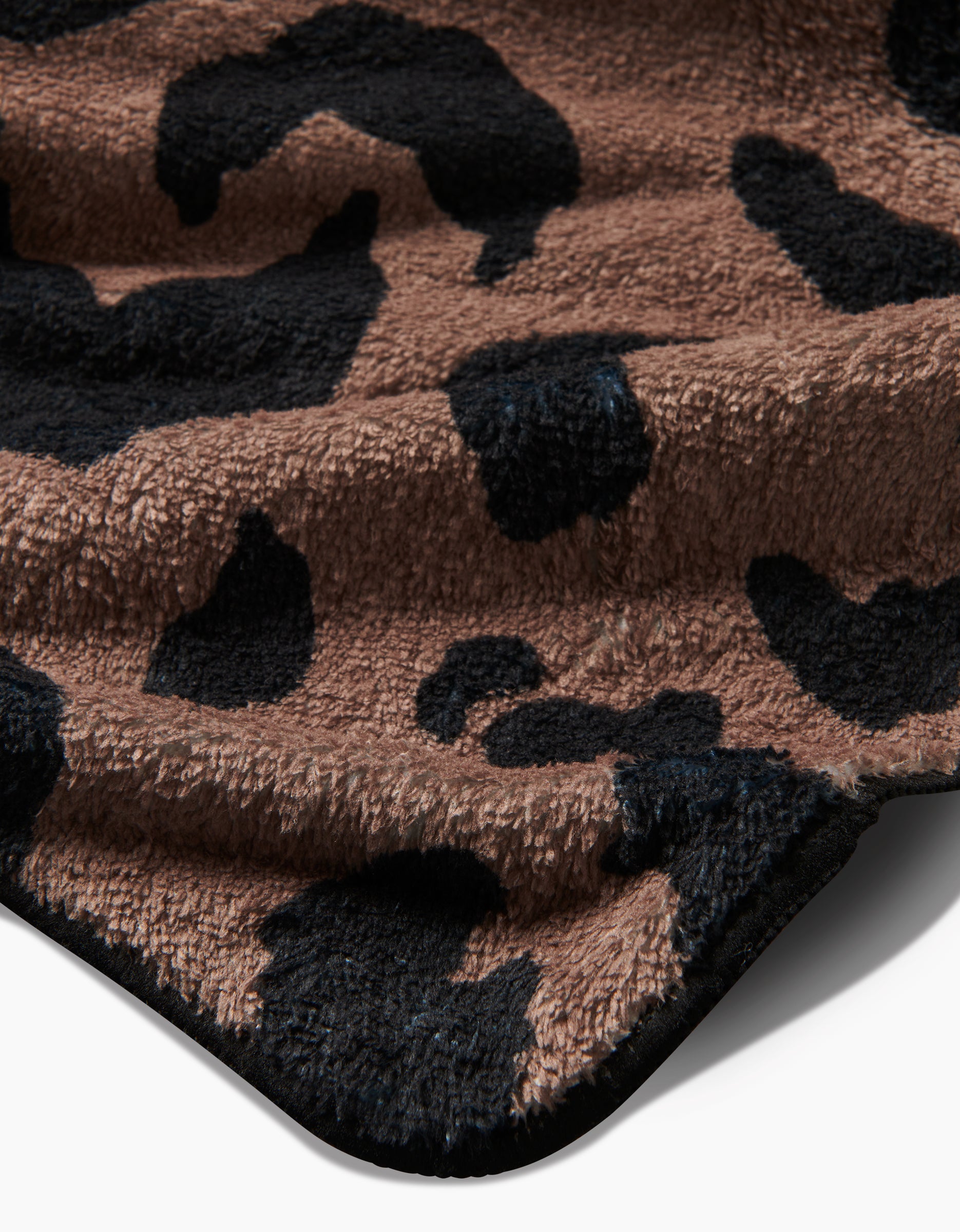 A close-up of Geometry’s Cheetah Hound fabric, made from recycled materials with a soft, plush texture and a brown-and-black leopard print. Light and shadow highlight its slightly wrinkled, fuzzy surface.