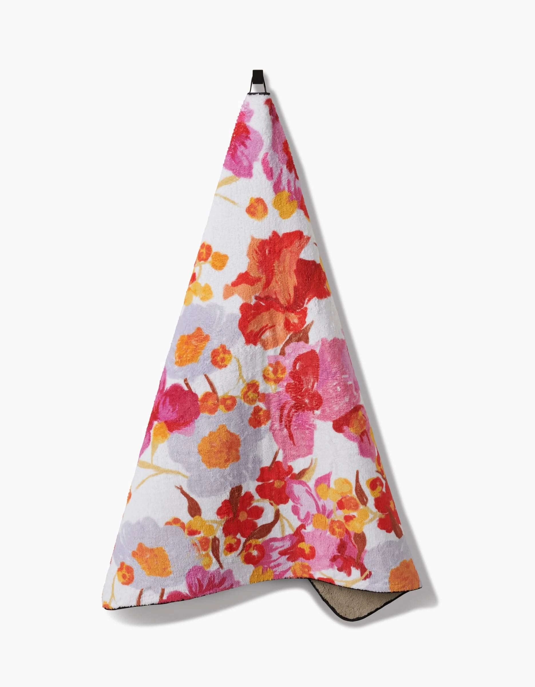 The Geometry Pup Florals towel is ultra-absorbent with a vibrant red, orange, pink, and purple floral design on white. It features a black hanging loop at the top for easy use.
