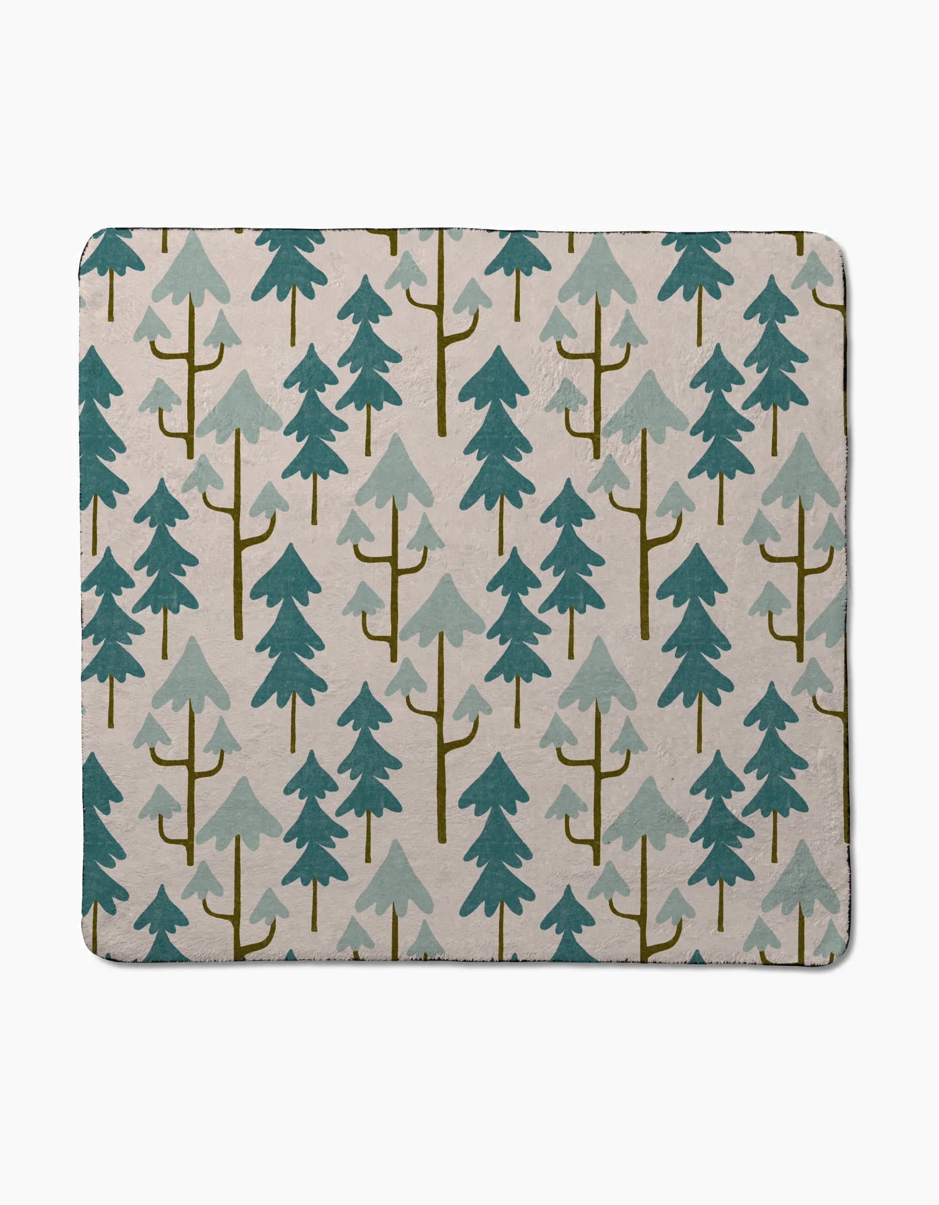 Clarence Light by Amy MacCready is a rectangular, ultra-absorbent dog towel with stylized teal and olive-green pine trees on a light beige background.