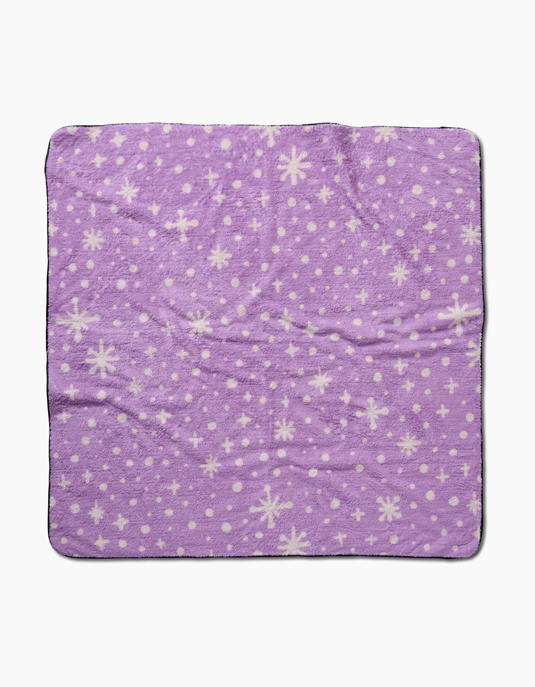 The Amy MacCready Estrella Purple is a soft, square plush dog towel featuring white snowflakes and dots on a purple surface, shown against a plain white background.