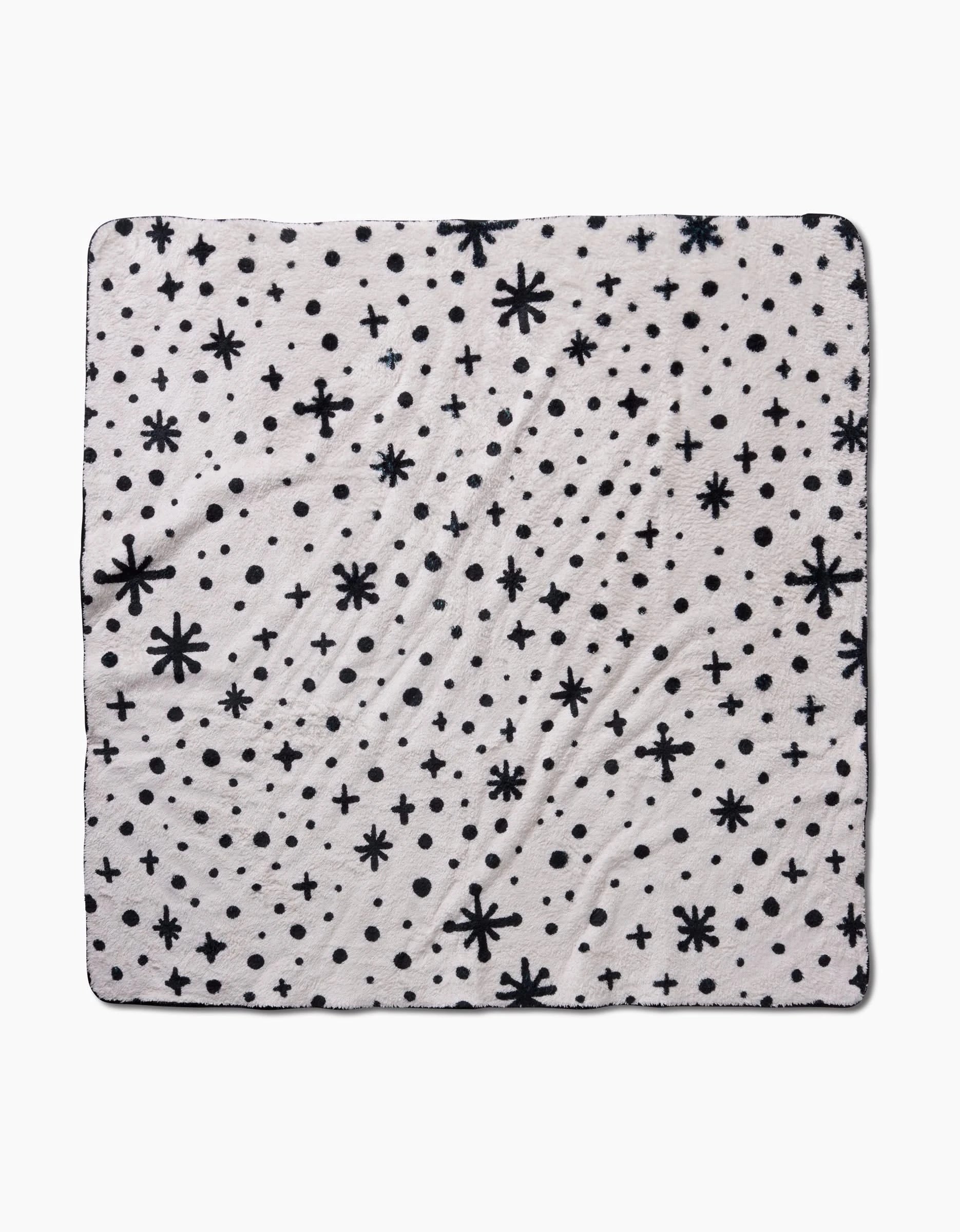 The Estrella White by Amy MacCready is a square, ultra-absorbent white dog towel with black stars, plus signs, and dots. Its blanket-style design features black edging for a stylish look.