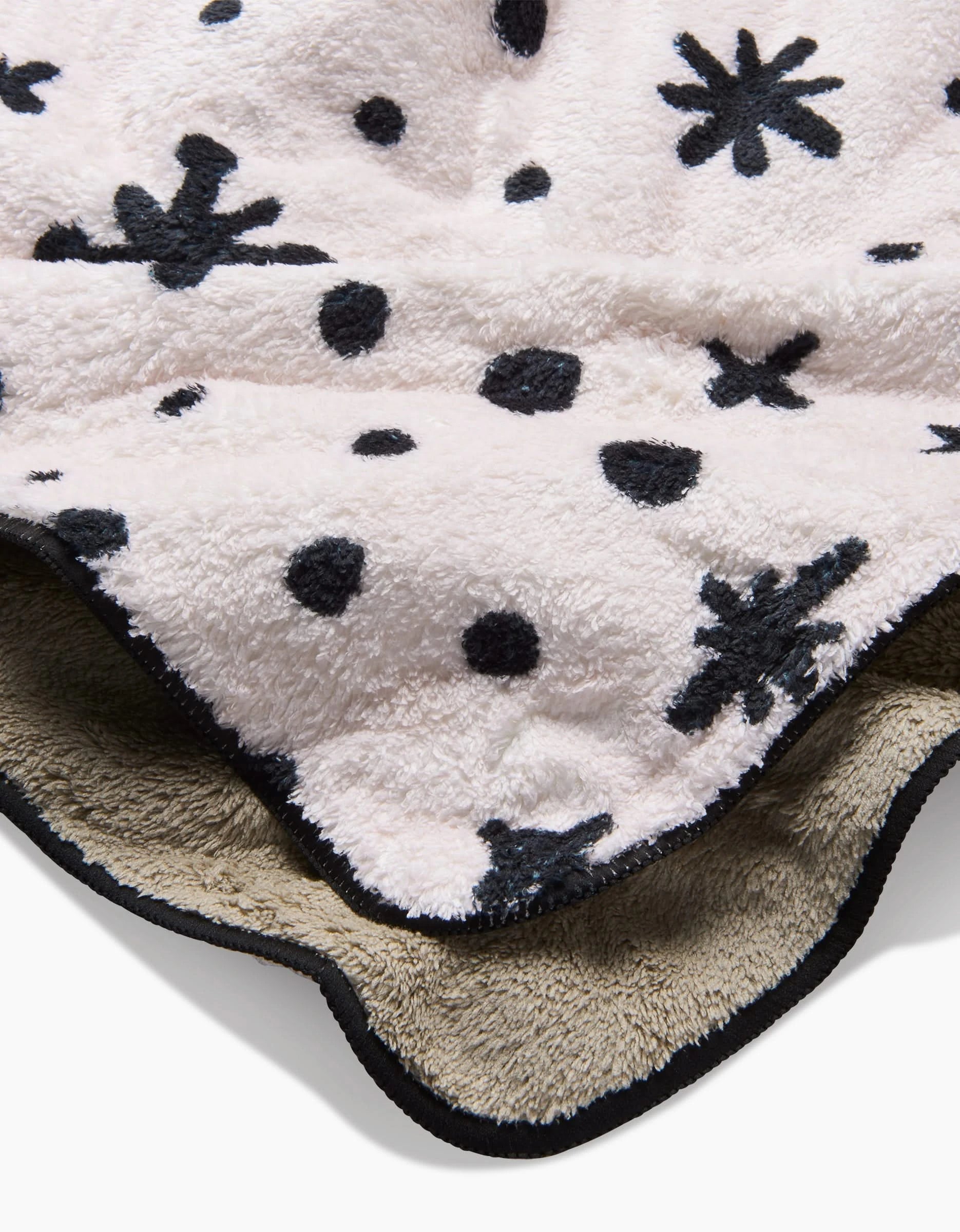 The Amy MacCready Estrella White is a soft, fluffy blanket with a cream top patterned with black stars, dots, and asterisks, plus a beige underside and black trim—crafted for cozy comfort like an ultra-absorbent dog towel.