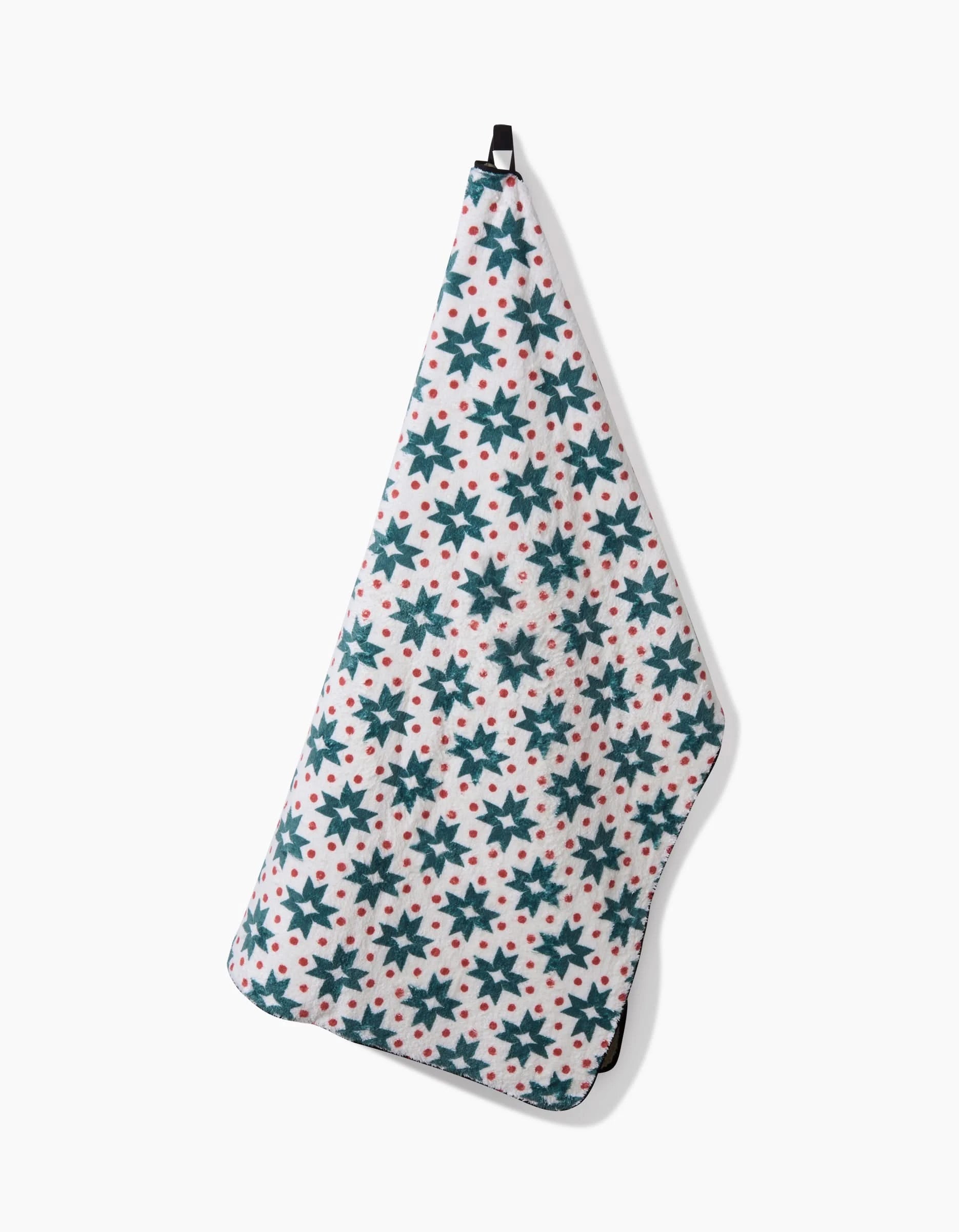 The Geo Star dog towel by Charlie Rowan Designs features a repeating pattern of dark green stars and small red dots, and hangs by a black loop against a plain white background.