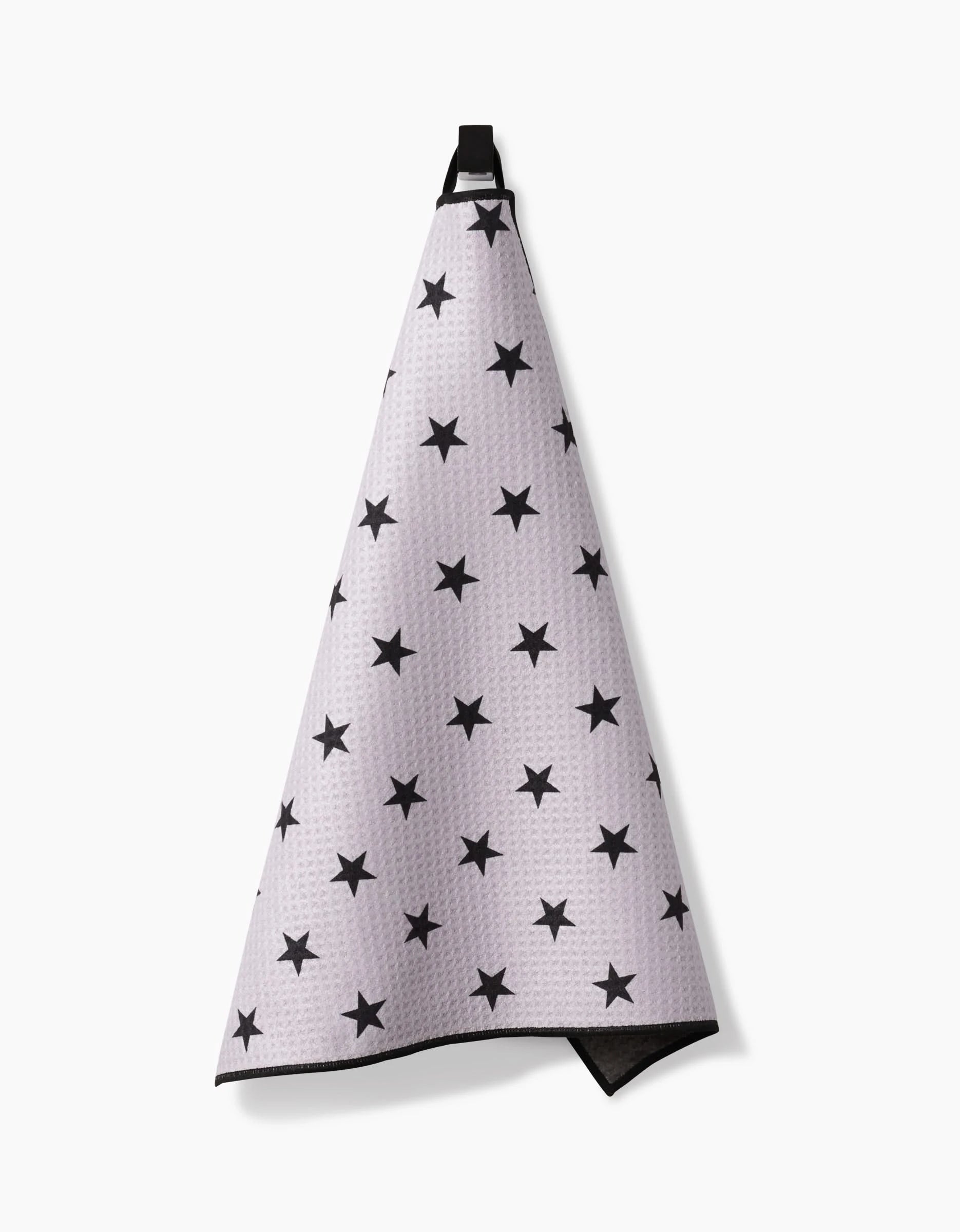 The Geometry Bark Paw Towel, made from ultra-absorbent Geoweave fabric, features a white texture with black star patterns and hangs by a black loop against a plain white background.
