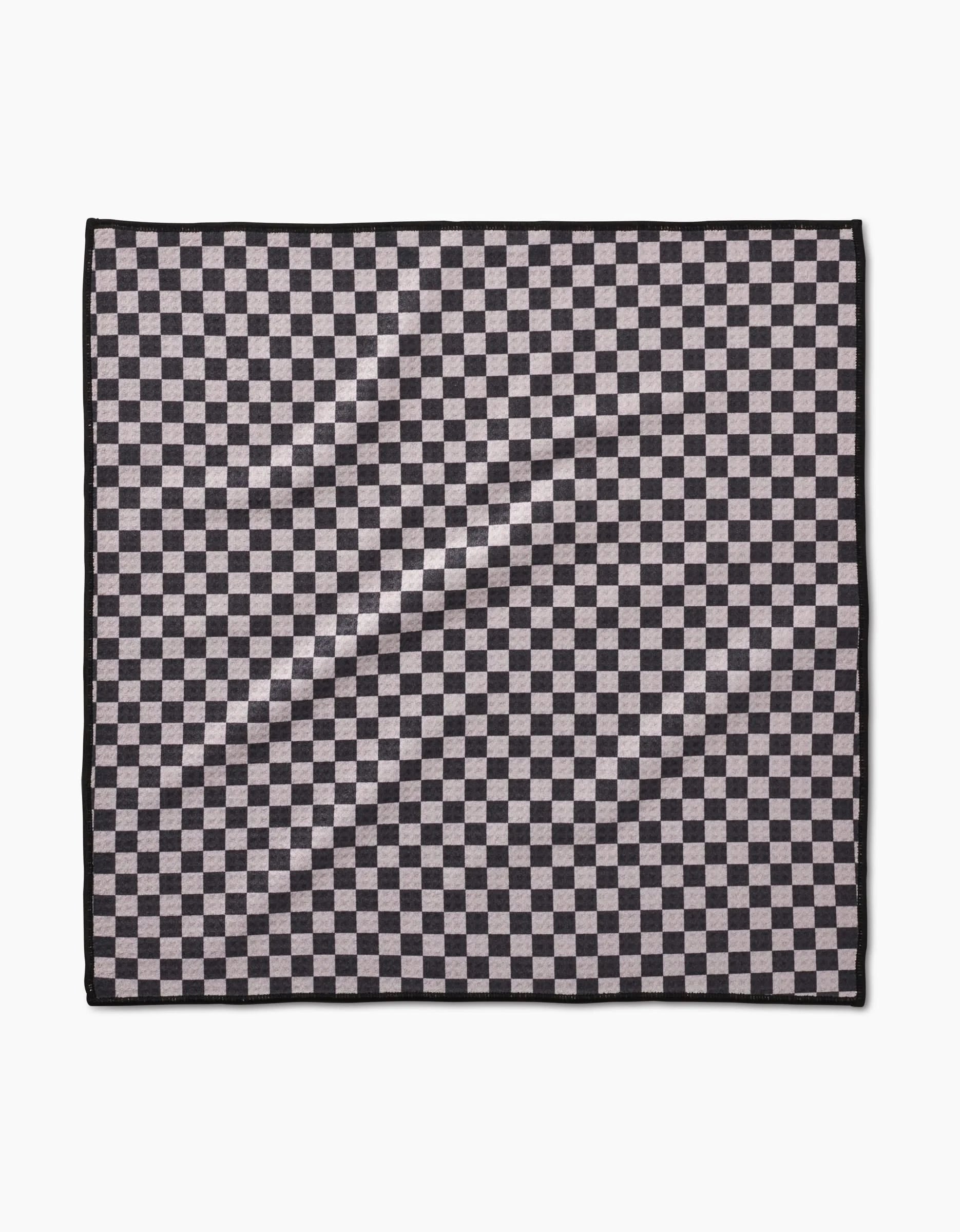 The Geometry Cool Pup Paw Towel features a black and grey checkerboard pattern with a thin black border. Made from ultra-absorbent Geoweave fabric, it’s shown on a white background.