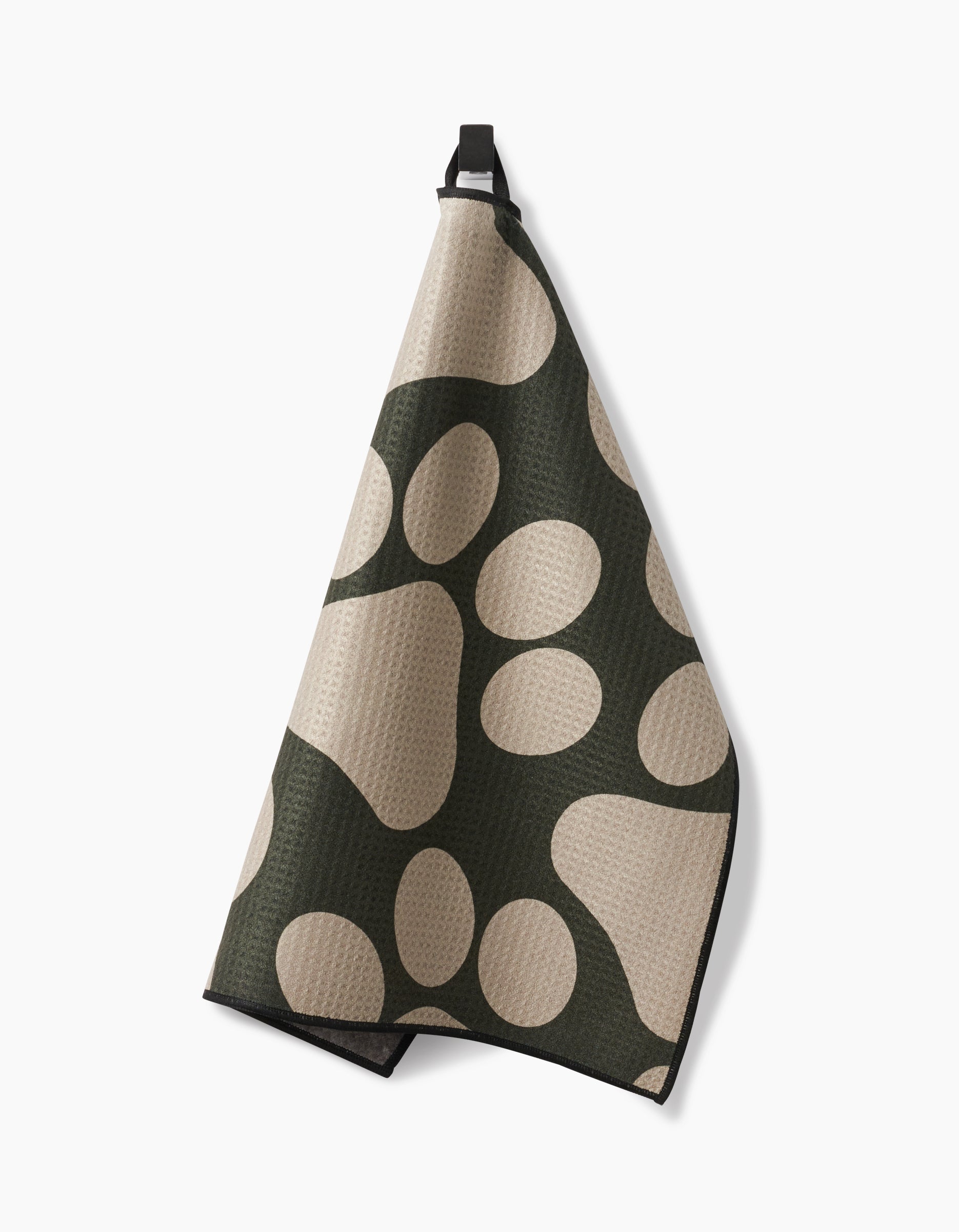 Geometrys Paw Prints kitchen towel features ultra-absorbent fabric in beige and dark green with an abstract oval pattern, shown hanging from a black loop on a plain white background.