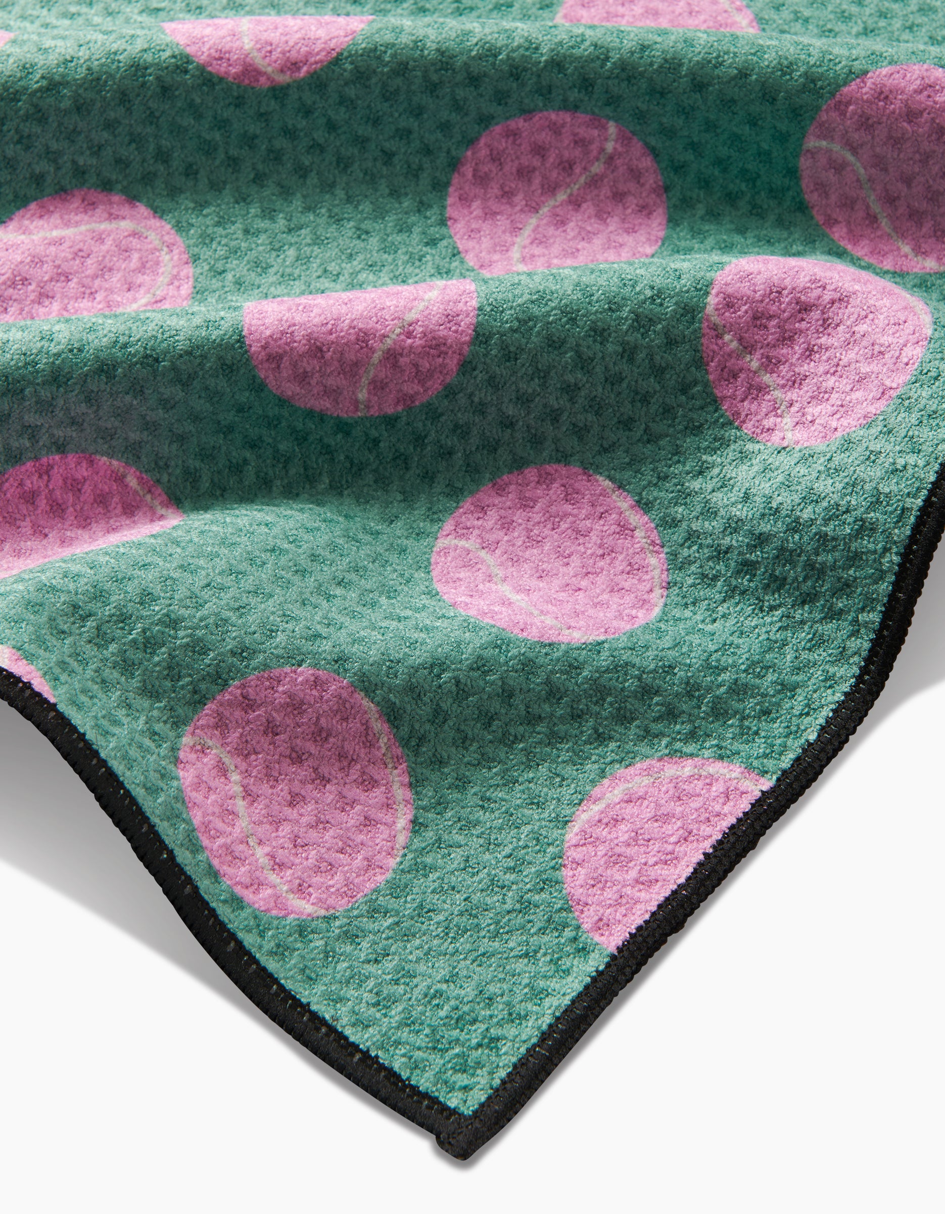 Geometry’s “Pink Ball” Paw Towel features green textured Geoweave fabric with large pink tennis balls and a black-edged border, partially folded to highlight its ultra-absorbent qualities—ideal for active pets.