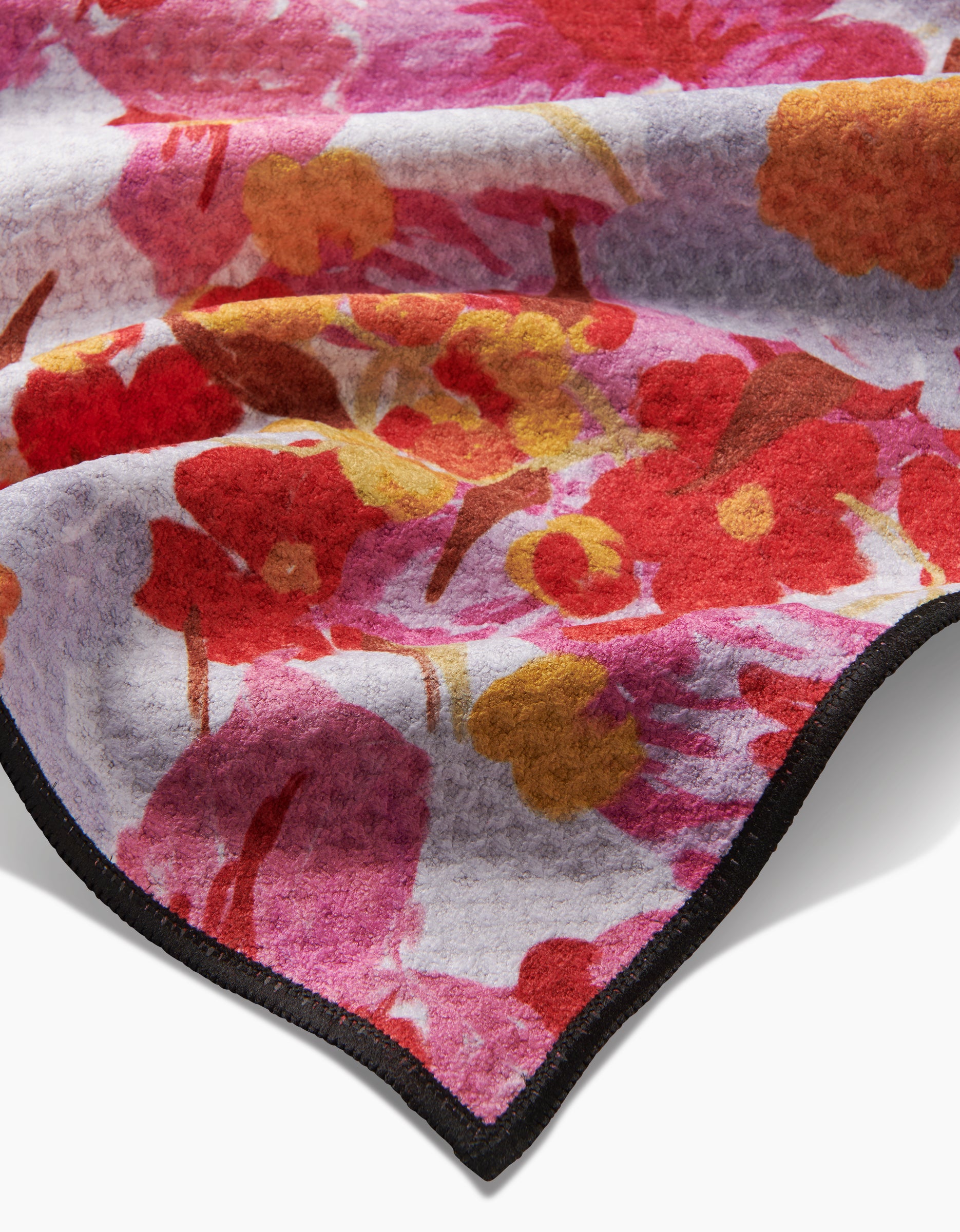 A close-up of the Geometry Pup Florals Paw Towel, made with ultra-absorbent Geoweave fabric, featuring a soft red, pink, and yellow floral pattern and a neatly stitched black edge.