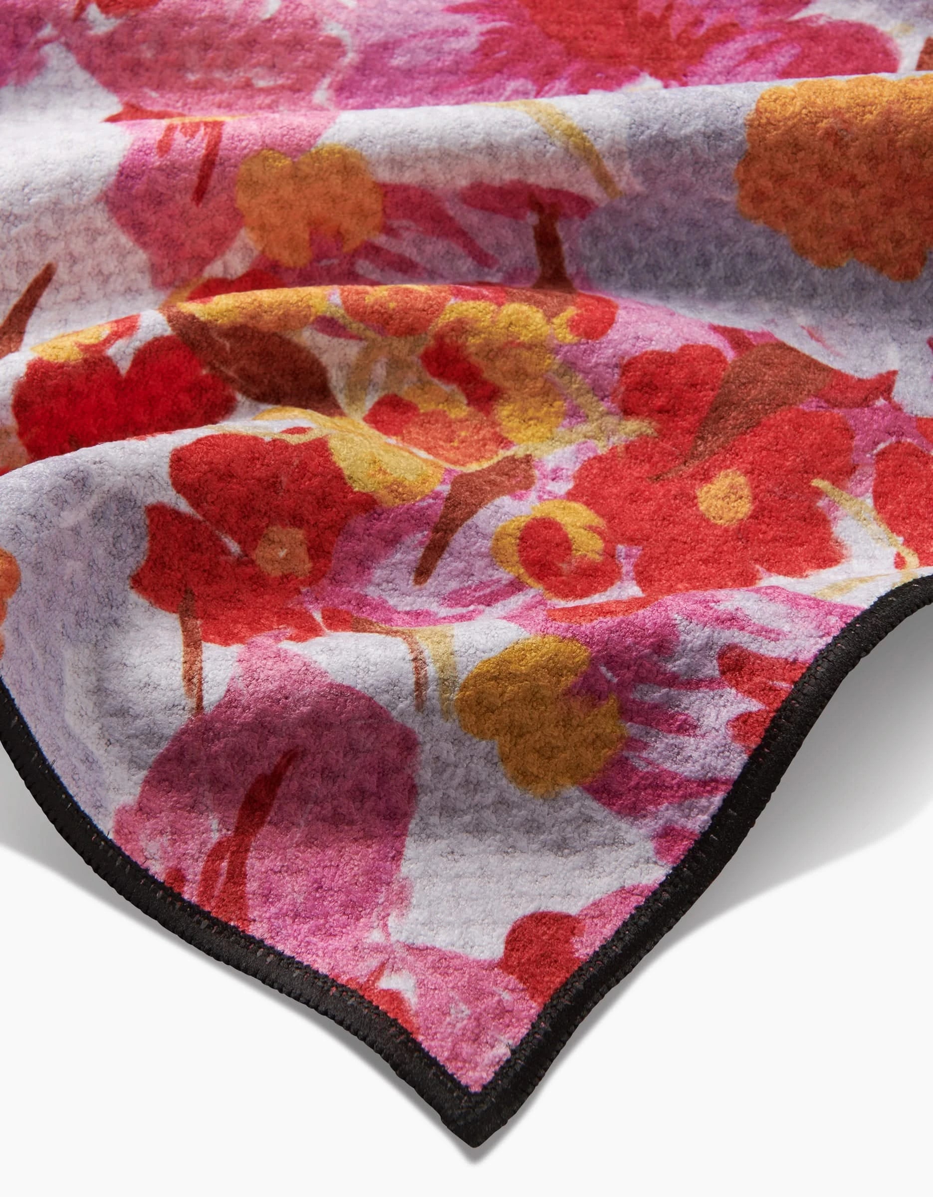 A close-up of the Geometry Pup Florals Paw Towel, made with ultra-absorbent Geoweave fabric, featuring a soft red, pink, and yellow floral pattern and a neatly stitched black edge.