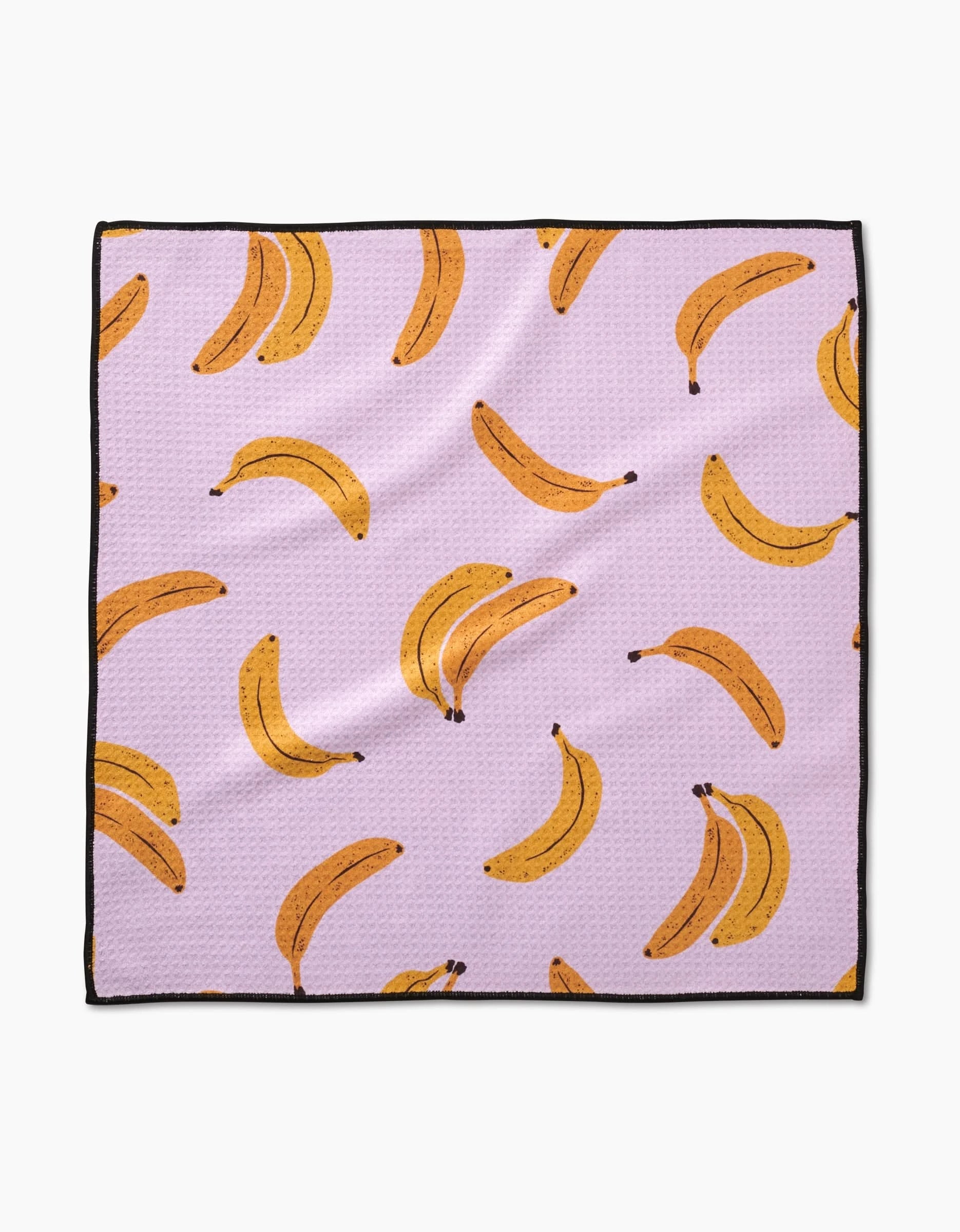 The Geometry Pupnana is a square Paw Towel with a light purple background, repeating yellow banana illustrations (single and in pairs), ultra-absorbent Geoweave fabric, and a sleek black border around the edges.