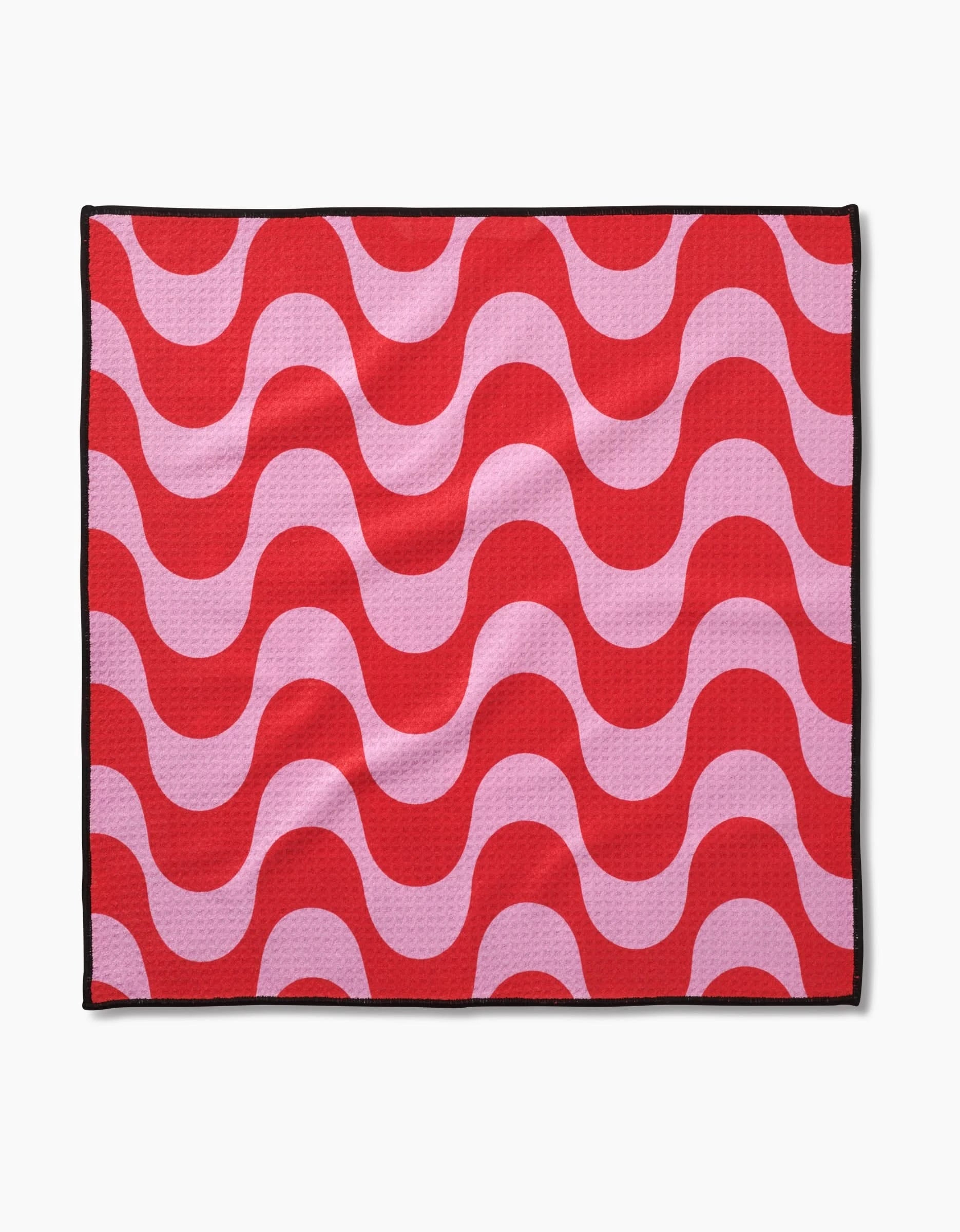 The Geometry Waves towel features ultra-absorbent Geoweave fabric with red and pink wavy stripes, a thin black edge, and a crisp white background.