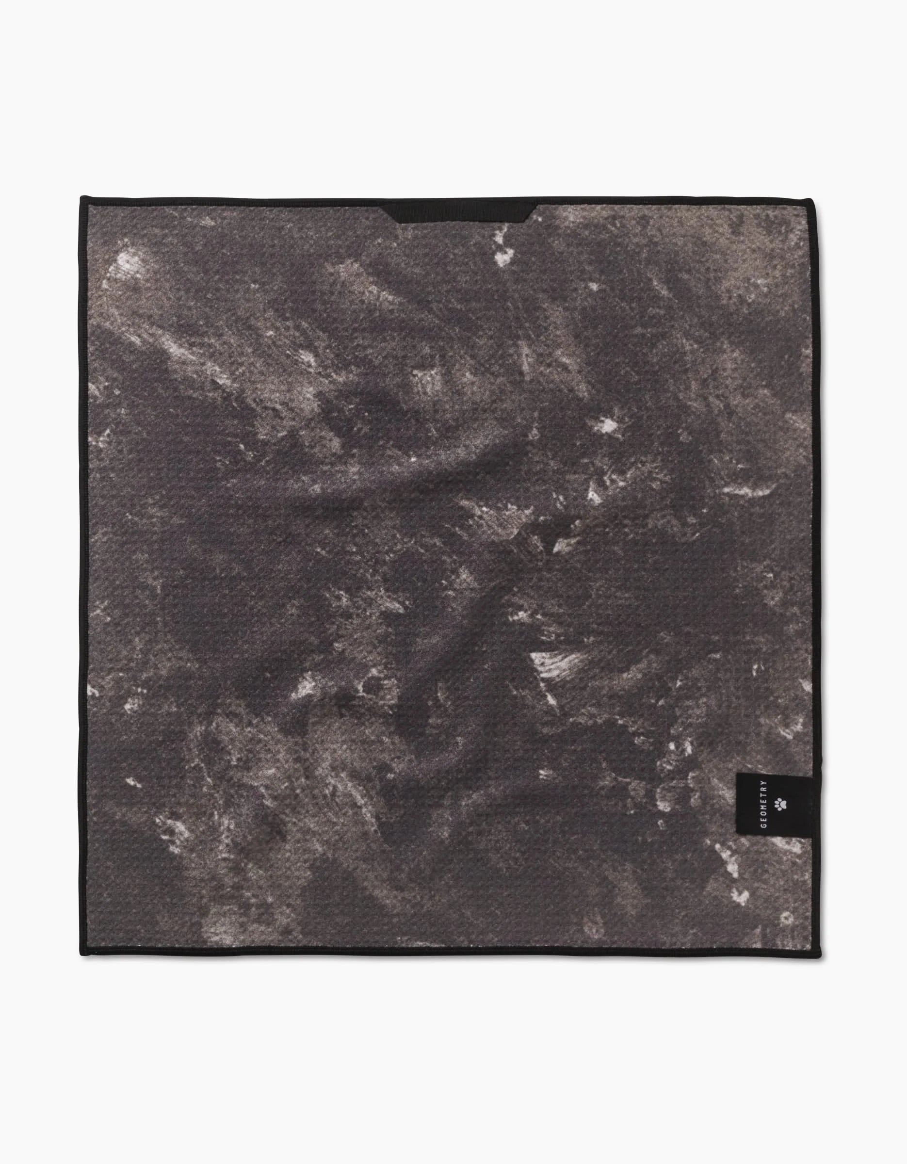 The Sweet Daisies by Geometry is a square, black Paw Towel made from ultra-absorbent Geoweave fabric, featuring a marbled gray and white design, black border, and a small black tag with white text in one corner.