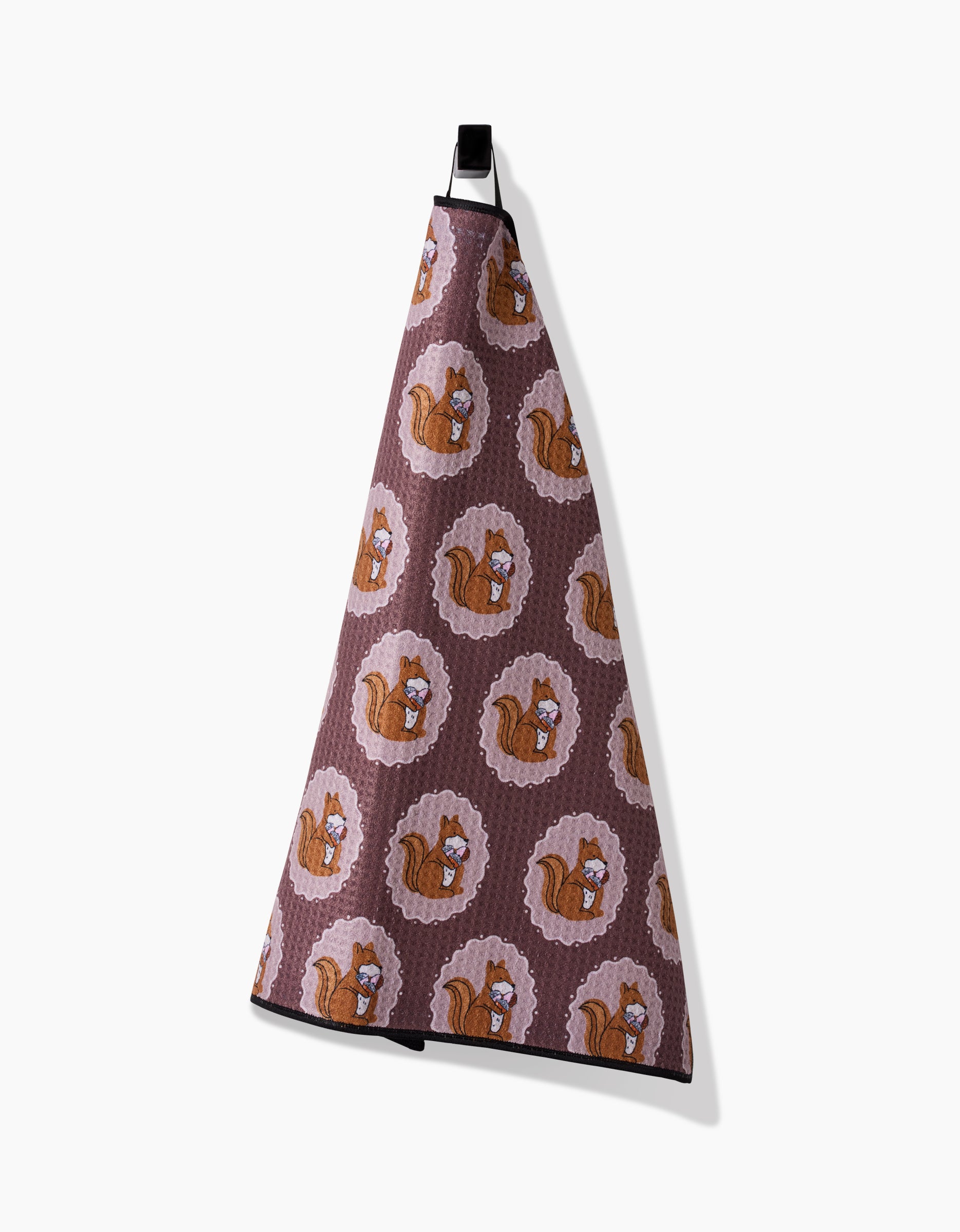 The Megan Roy Squirrels Brown Paw Towel, crafted from ultra-absorbent Geoweave fabric and adorned with cartoon squirrels holding acorns, hangs by a black loop against a white background.