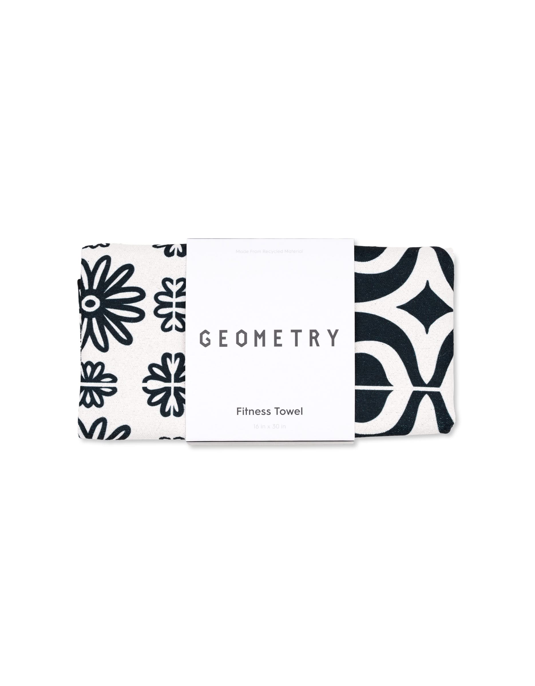 A black and white ultra-absorbent GEOMETRY fitness towel, folded and wrapped with a label, featuring geometric and floral patterns. Product name: Magna - Bohemian Mosaic.