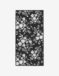 The Botanical Silhouettes Charcoal by Danelys Sidron is a rectangular fitness towel with a black background and white floral silhouettes, crafted from recycled materials for an elegant, eco-friendly touch.
