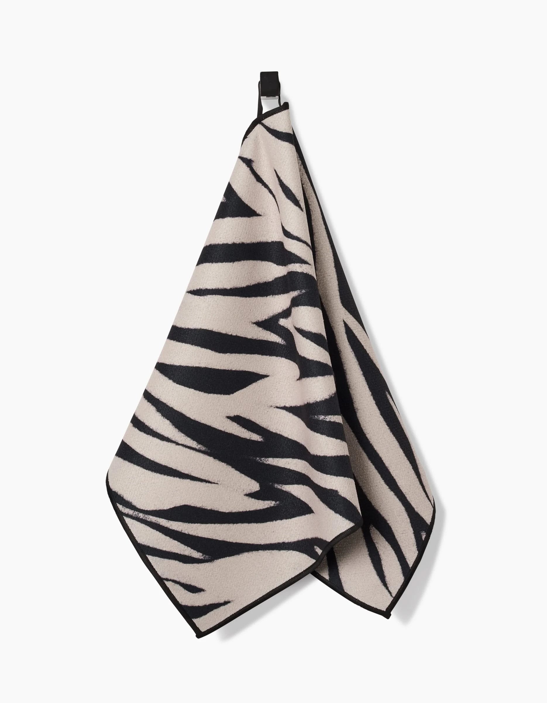 The Chase fitness towel by GEOMETRY features a black and beige zebra stripe design, is made from recycled materials, and is displayed on a white background.