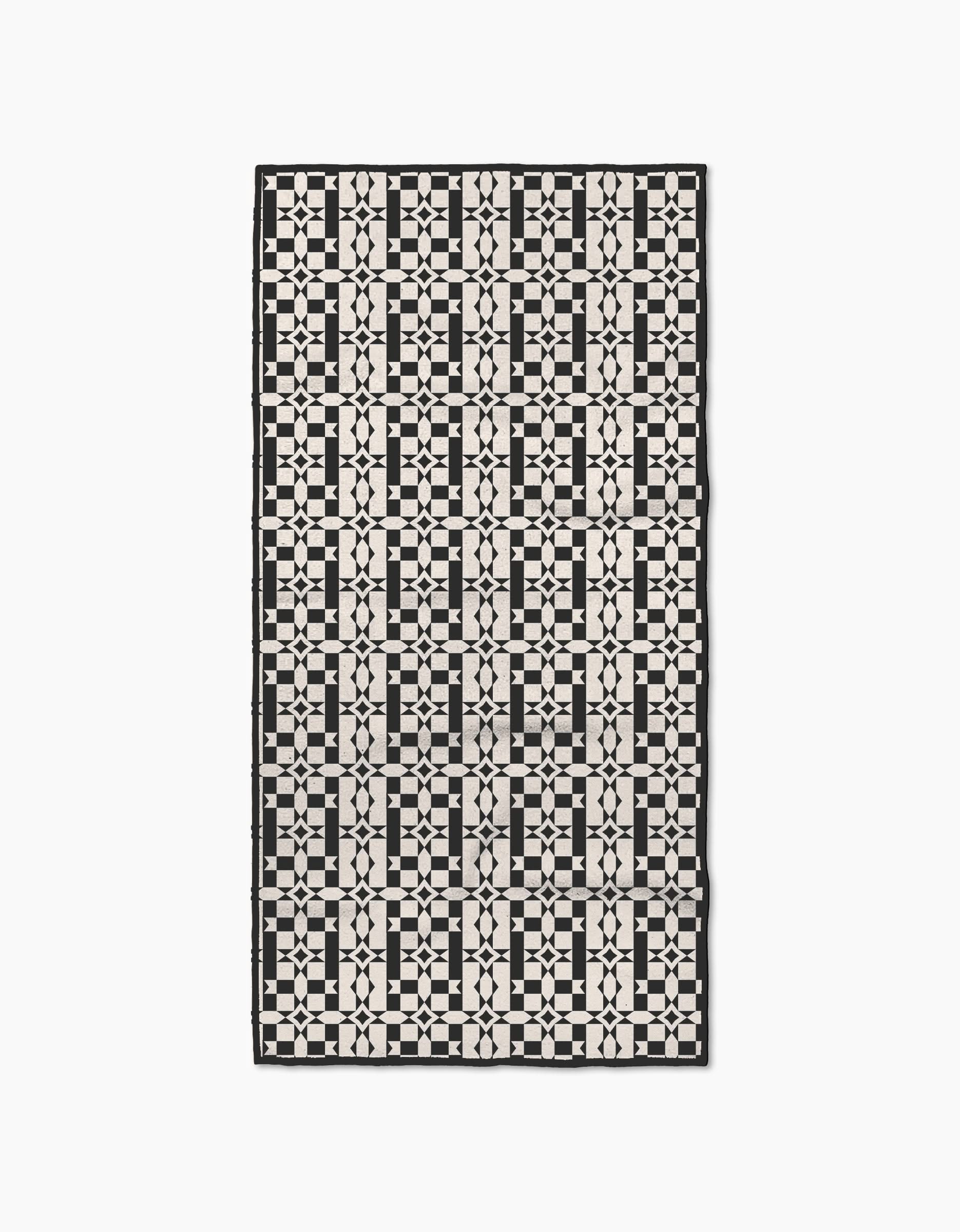 The Intermission rug by Geometry is a rectangular piece made from recycled materials, featuring a modern, symmetrical black and white geometric pattern of squares, circles, and intersecting lines.