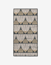 The Letitia rug by Amy MacCready features a repeating geometric fan design with dotted accents in black, beige, and cream, arranged in horizontal rows on a light background. Made from recycled materials.