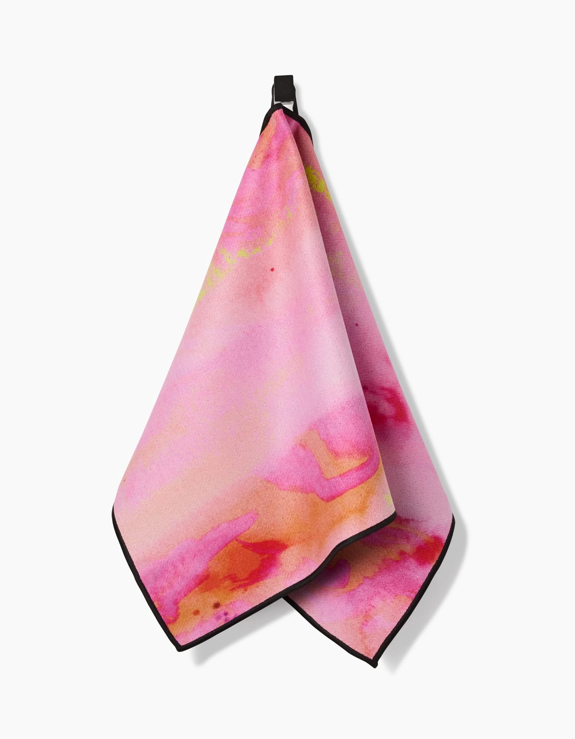 The GEOMETRY Purity towel, featuring pink with orange and yellow watercolor-style patterns and a black hanging loop, is displayed against a white background.
