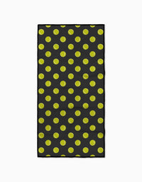 The Geometry Serve fitness towel features a black background with a repeating yellow tennis ball pattern and is made from ultra-absorbent recycled materials.