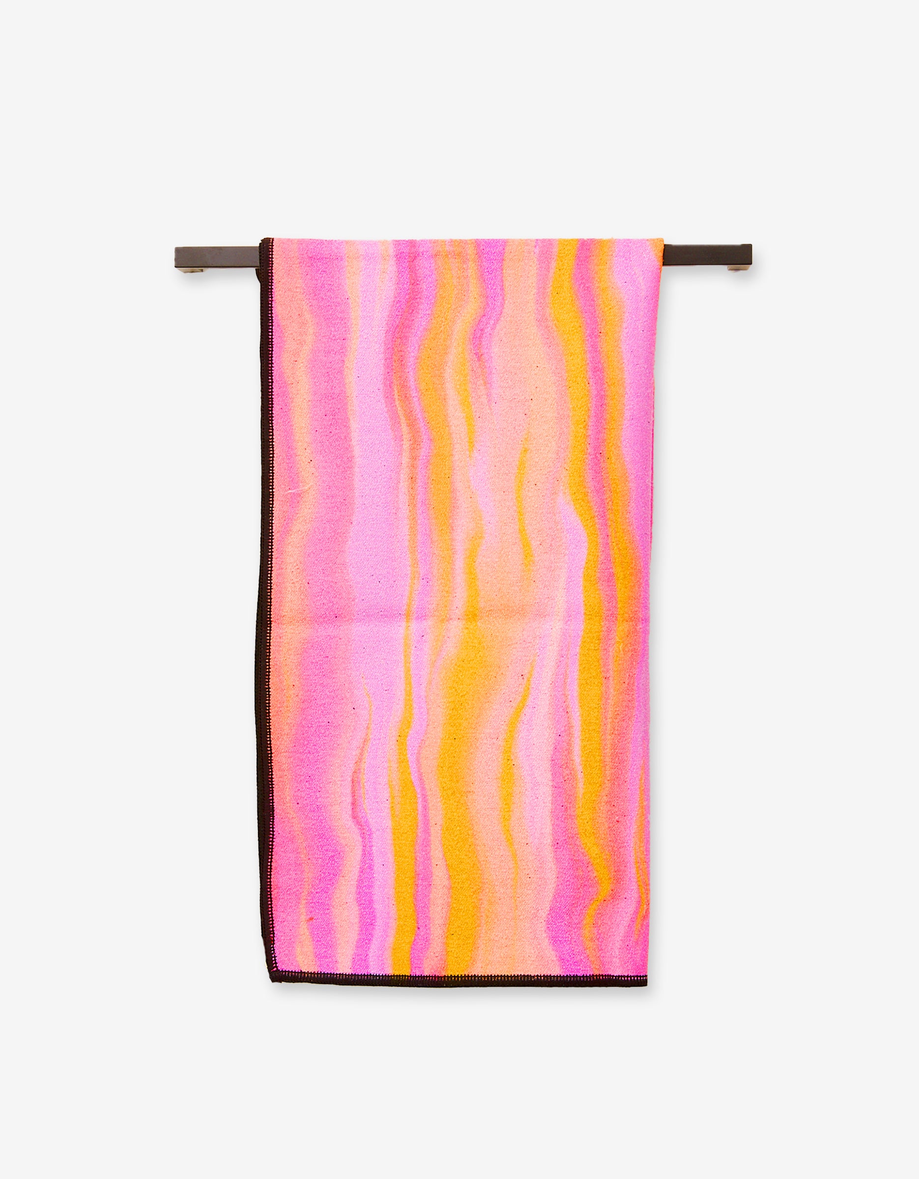 The Rush by GEOMETRY, an ultra-absorbent towel featuring a wavy, marbled pattern in pink, yellow, and orange tones, hangs neatly on a horizontal bar against a plain white background.