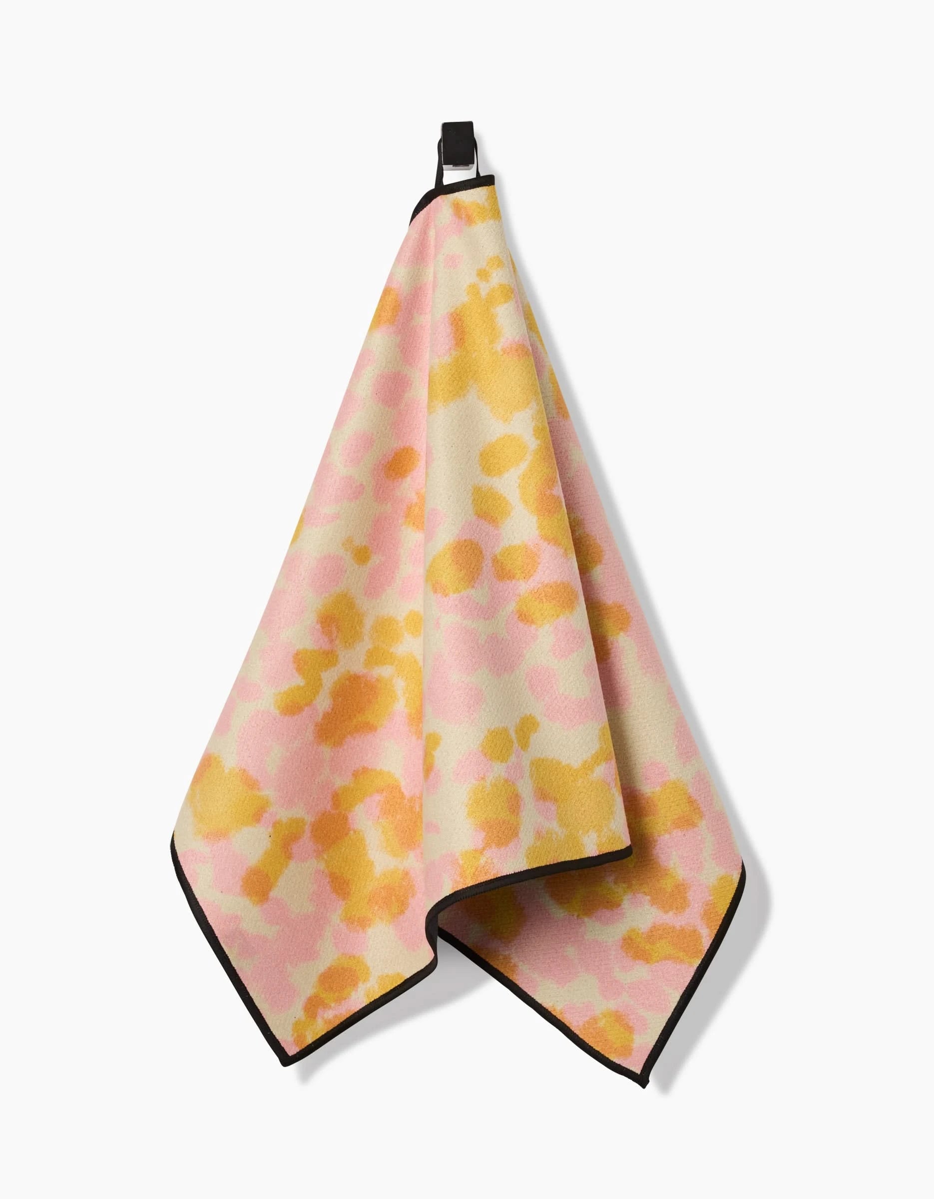 The Whimsy fitness towel by GEOMETRY features a pink and yellow abstract pattern with black borders and a hanging loop. Made from recycled materials, it offers style, sustainability, and ultra-absorbency.