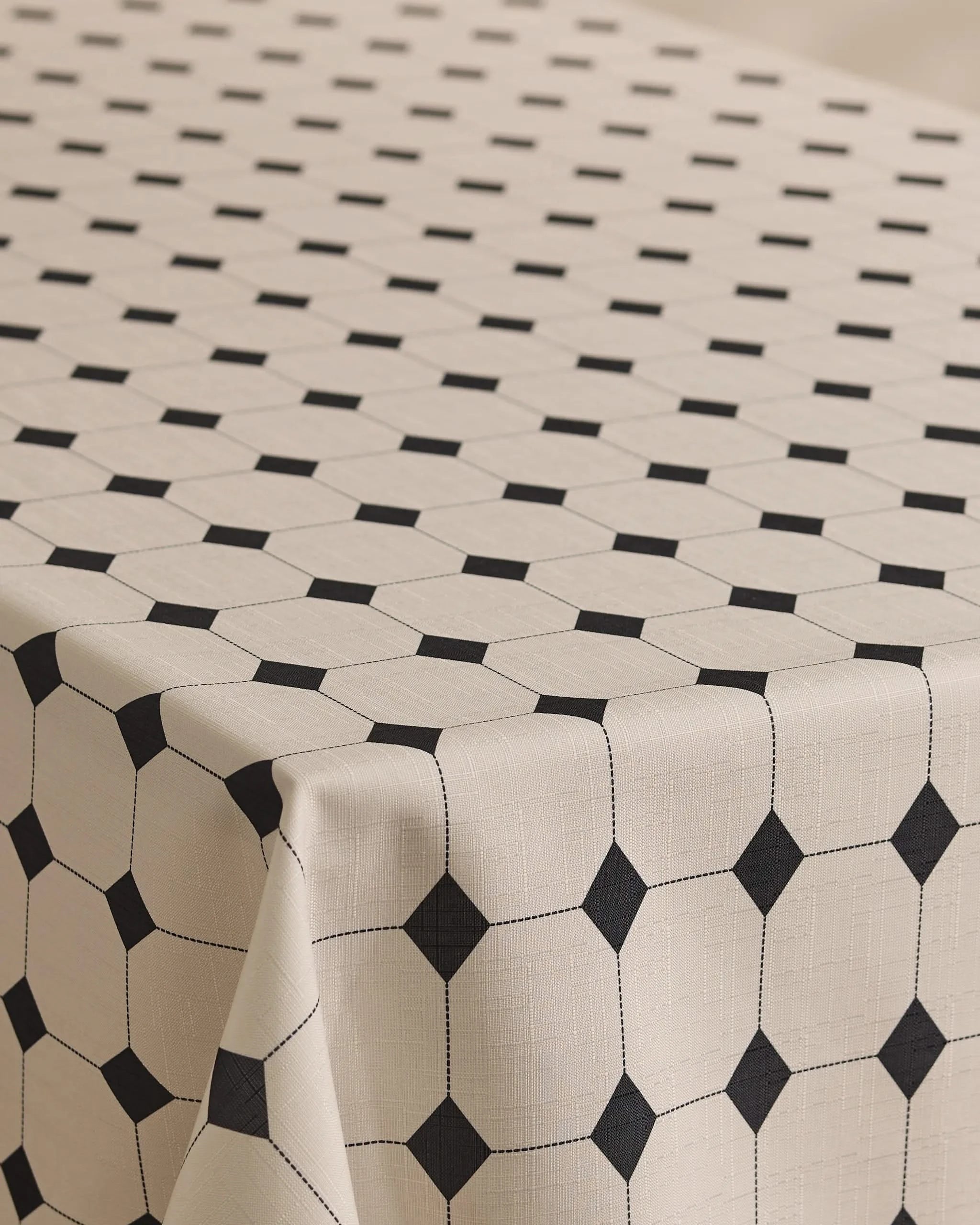 The Espresso Mosaic tablecloth by Geometry is lightweight, stain-resistant, and beige, featuring a stylish grid of black squares and lines that form octagonal shapes for a modern table look.